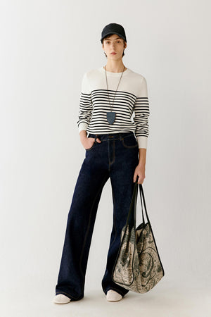 Full-length front view showing the top styled with wide-leg ivory trousers, emphasizing the overall proportions, the contrast between the dark navy shade and the light base, and the way the top follows the body with a close, fluid fit
