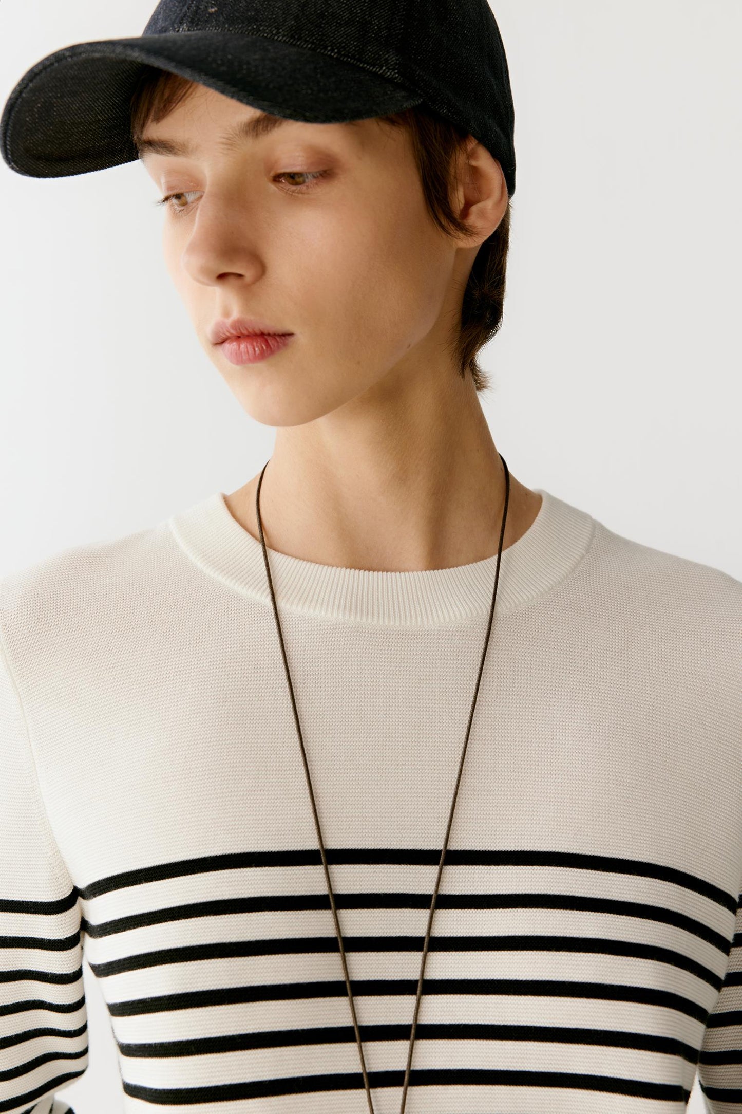 Close-up portrait of the upper body focusing on the neckline and shoulder line, showing the sleeveless cut, fine knit structure and the slightly sheer, breathable quality of the openwork vertical pattern