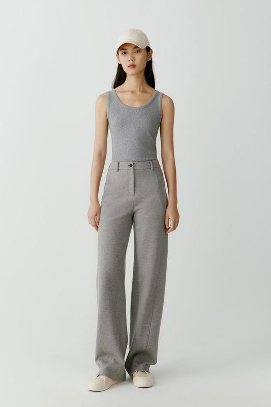 Full-length view showing the tank top paired with relaxed trousers. The image emphasizes the fluid fit, lightweight rib jersey construction and streamlined proportions of the garment.