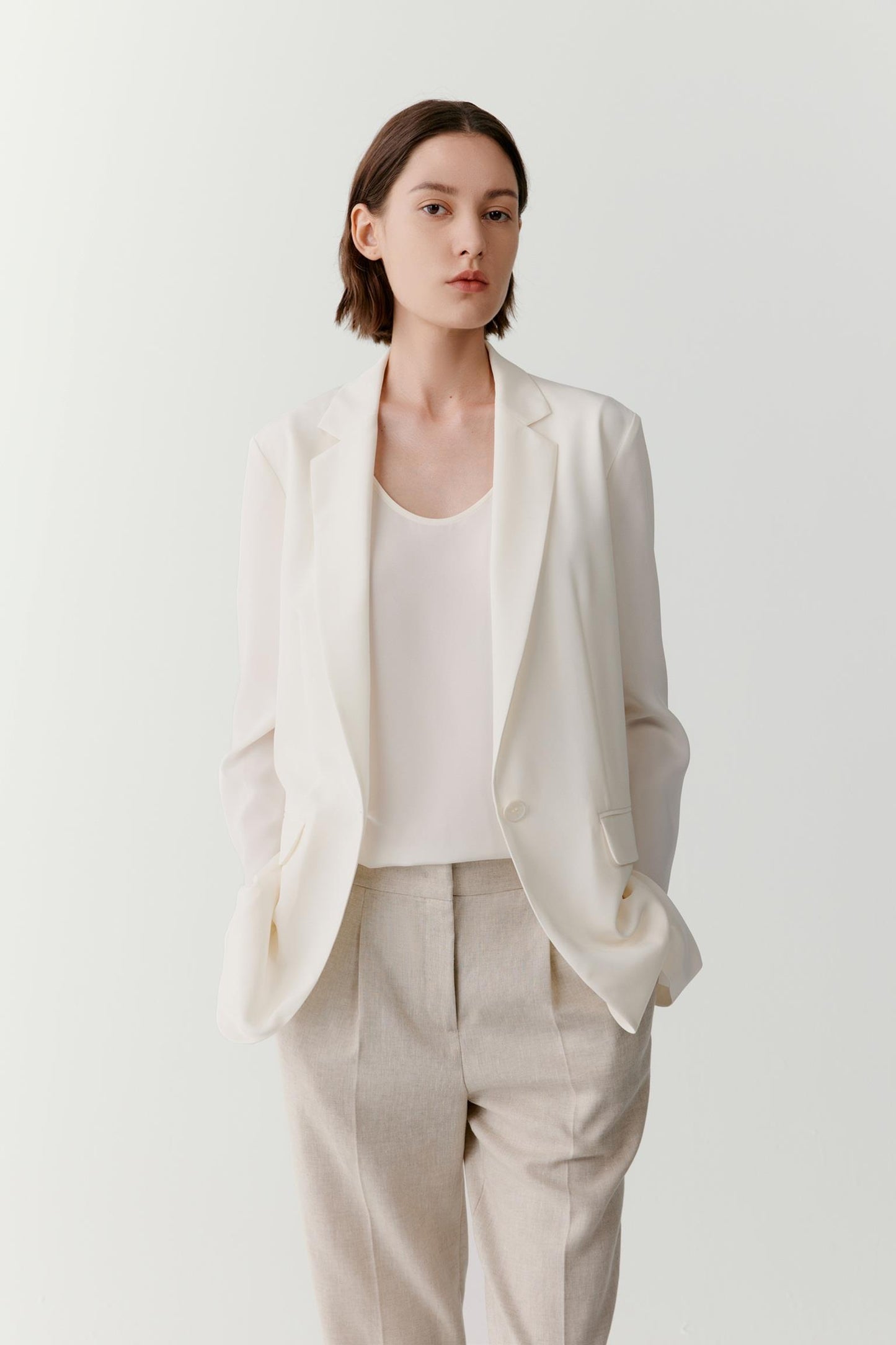 Three-quarter view showing the full silhouette and relaxed tailoring of the blazer. The image emphasizes the fluid movement of the silk crêpe de Chine, the clean lines of the construction and the balanced proportions created by the softly structured shape.