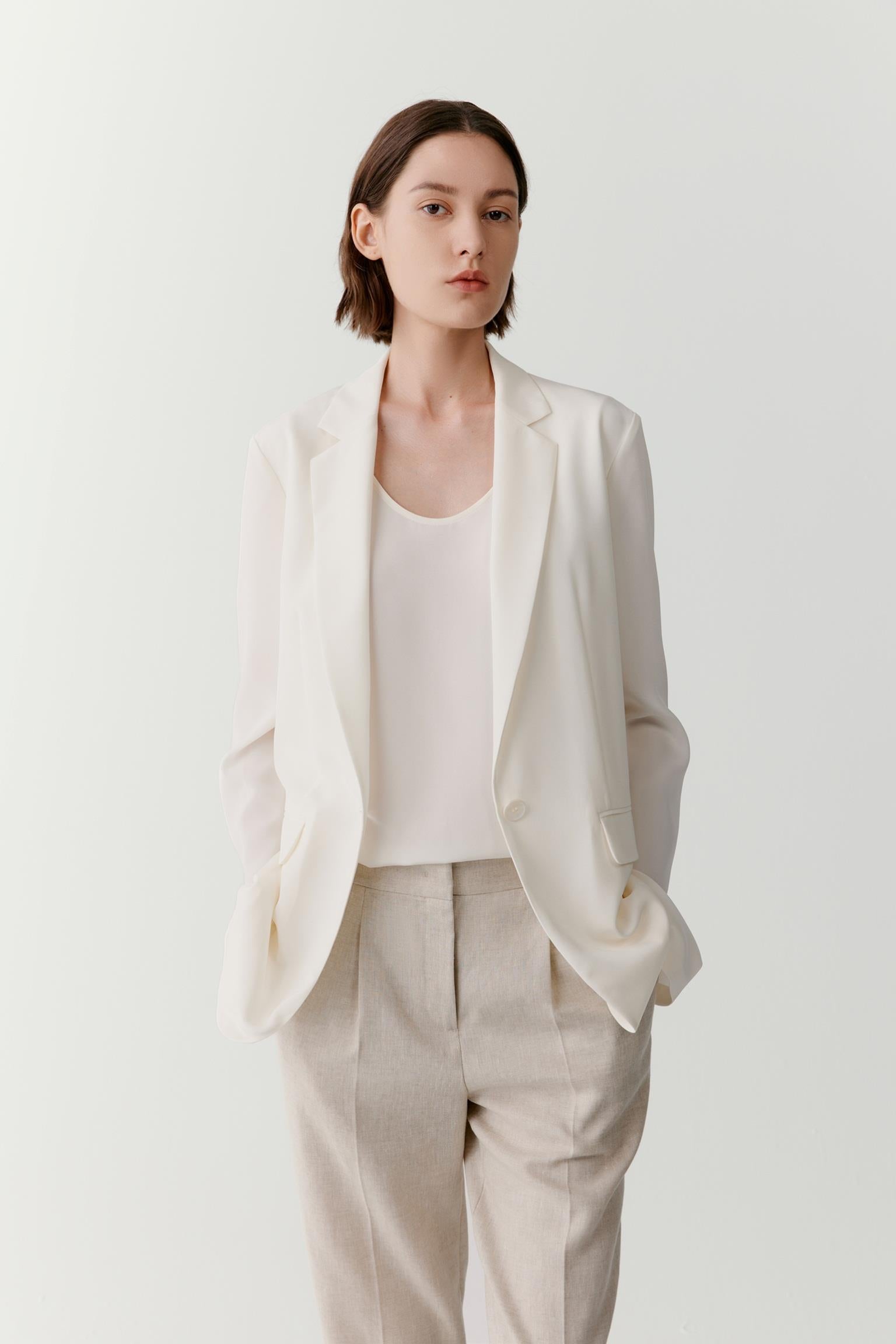 Three-quarter view showing the full silhouette and relaxed tailoring of the blazer. The image emphasizes the fluid movement of the silk crêpe de Chine, the clean lines of the construction and the balanced proportions created by the softly structured shape.