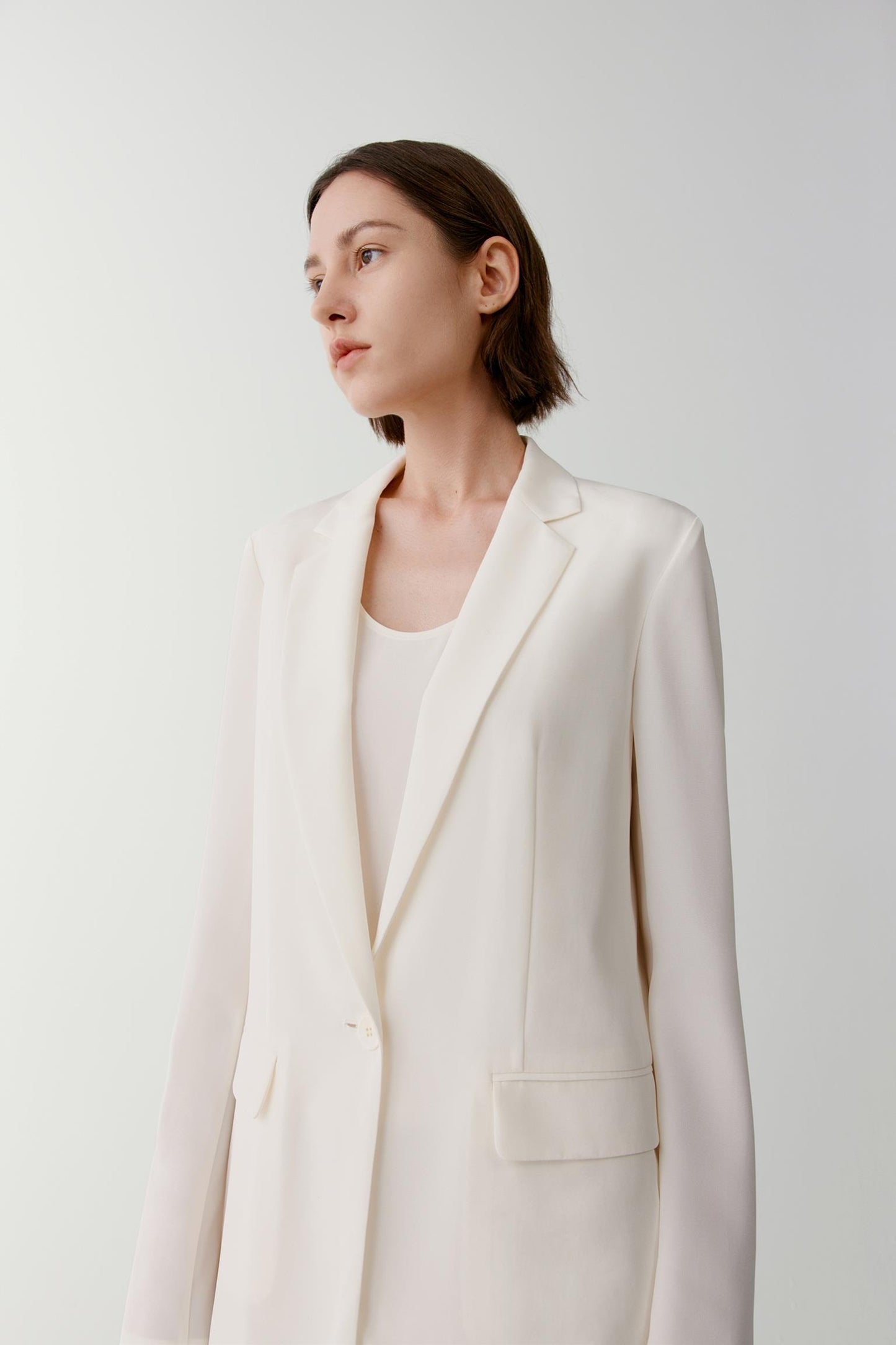Close-up portrait focusing on the notched lapels, neckline and upper-body construction. The image reveals the smooth texture, soft hand and subtle lustre of the silk fabric while showcasing the precise tailoring and clean finishing.