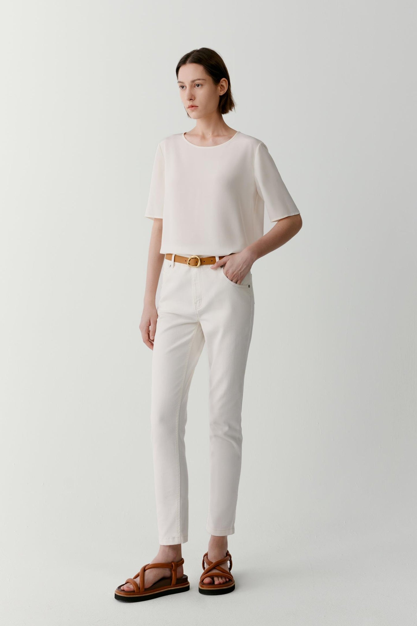 Full-length front view showing the balanced proportions of the relaxed silhouette. The lightweight silk crêpe de Chine drapes softly over the body, creating gentle movement and a fluid outline enhanced by the clean construction and minimal detailing.