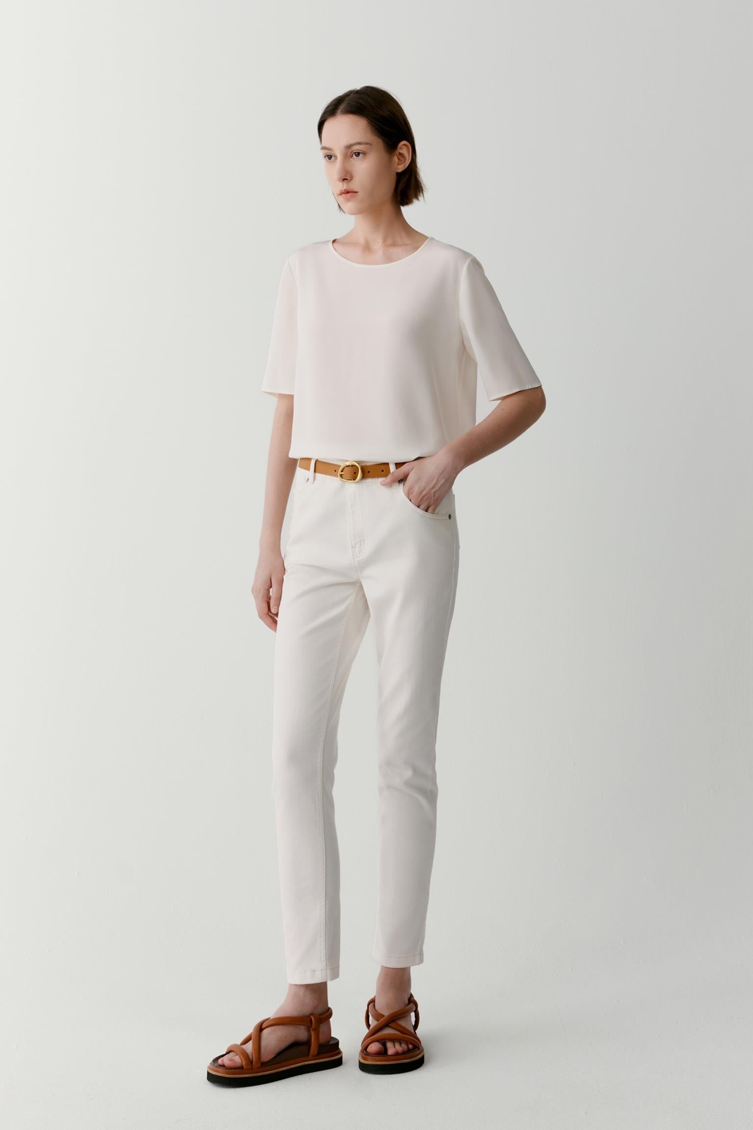 Full-length front view showing the balanced proportions of the relaxed silhouette. The lightweight silk crêpe de Chine drapes softly over the body, creating gentle movement and a fluid outline enhanced by the clean construction and minimal detailing.