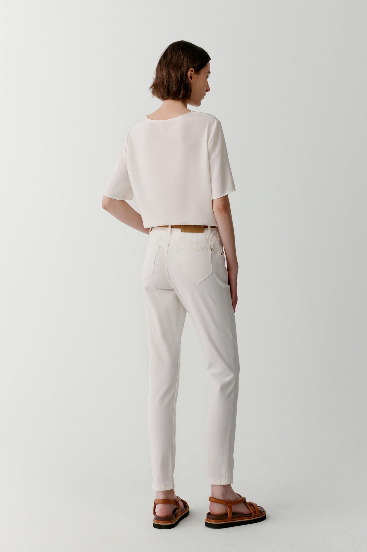 Three-quarter view highlighting the fluidity of the fabric and the ease of the cut. The image emphasizes the soft structure of the short sleeves, the smooth surface of the silk and the natural fall of the garment through the body.