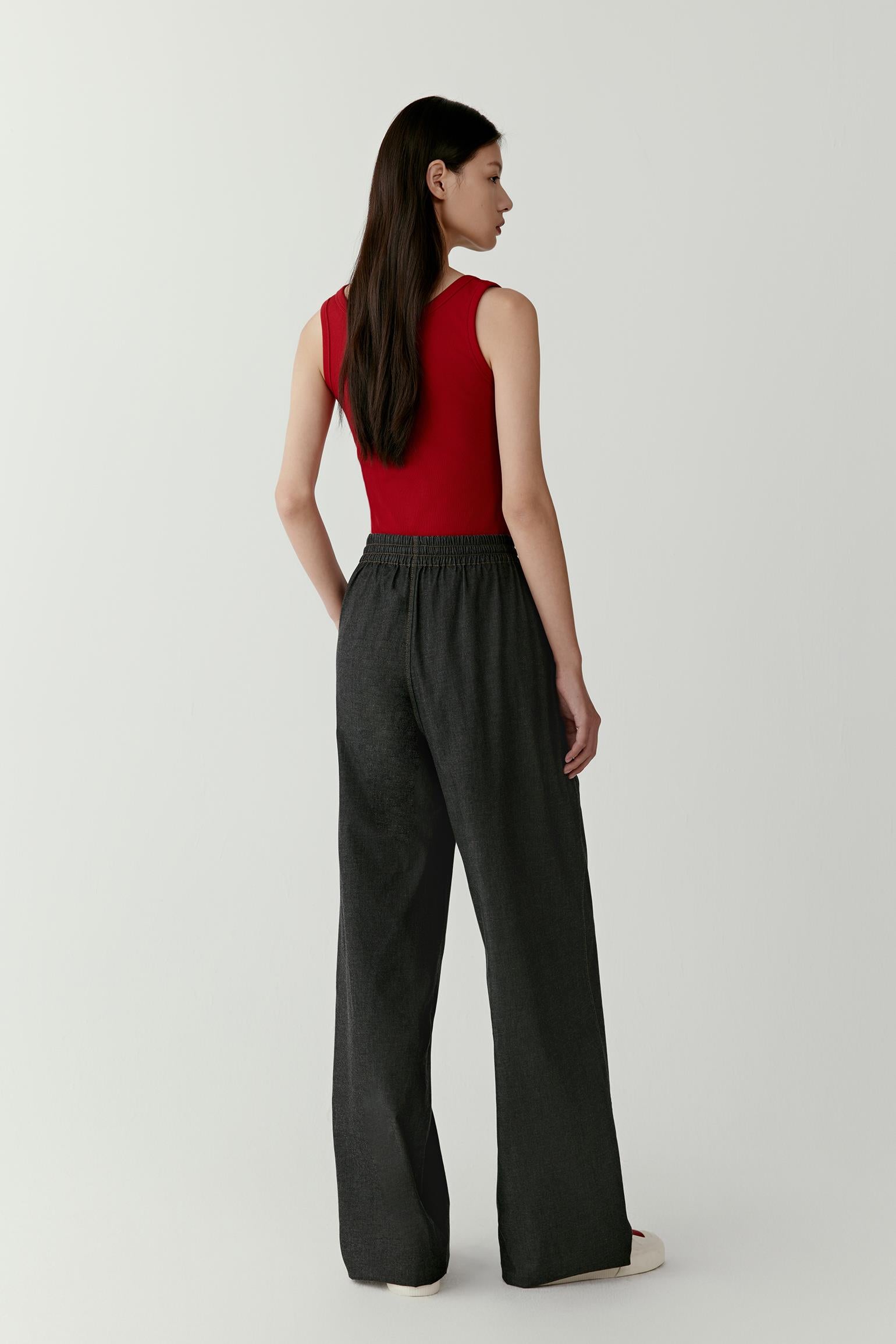 Back view illustrating the close fit and natural stretch of the rib jersey fabric. The garment follows the contours of the body while maintaining a clean outline, and the sleeveless cut enhances the lightweight, versatile character of the design.
