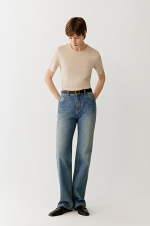 Full-length front view showing the T-shirt styled with blue denim trousers. The straight cut, round neckline and short sleeves create balanced proportions, while the lightweight jersey construction allows the garment to follow the body with ease.