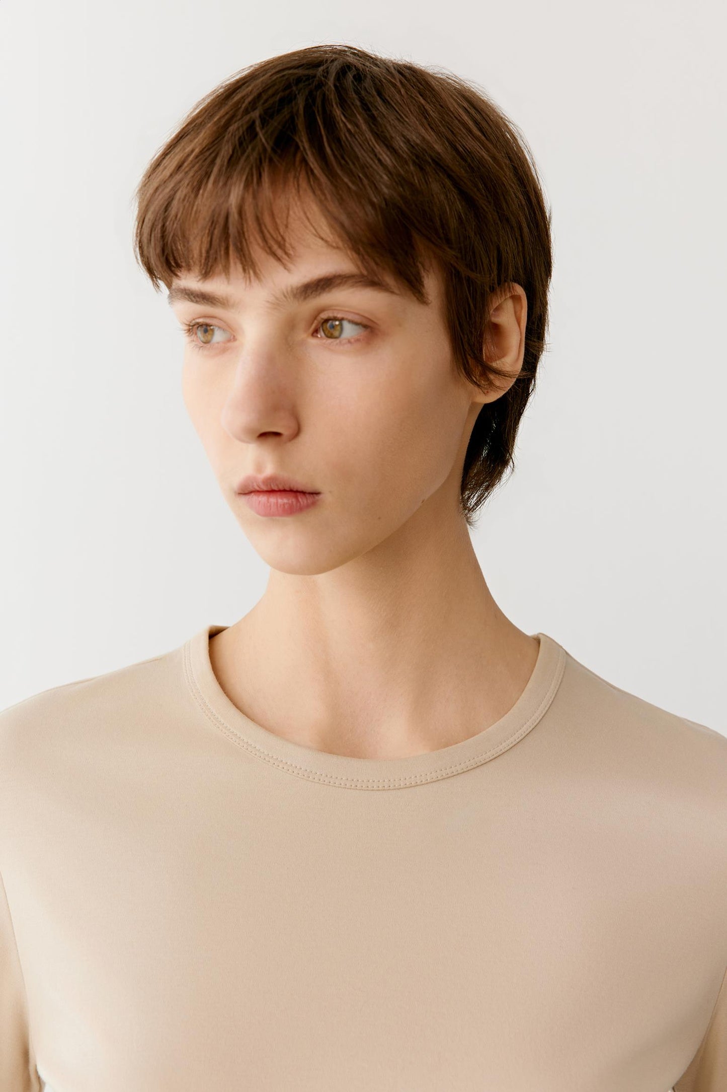 Close-up portrait focusing on the round neckline, shoulder construction and upper body. The image highlights the even jersey knit, smooth matte surface and soft texture, while showcasing the clean finishing and minimal design of the garment.
