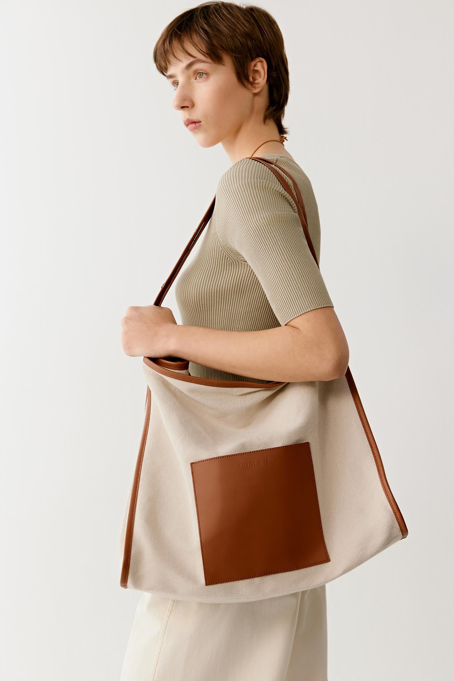 Side view highlighting the wide shoulder straps and the softly structured silhouette designed for comfortable everyday use.