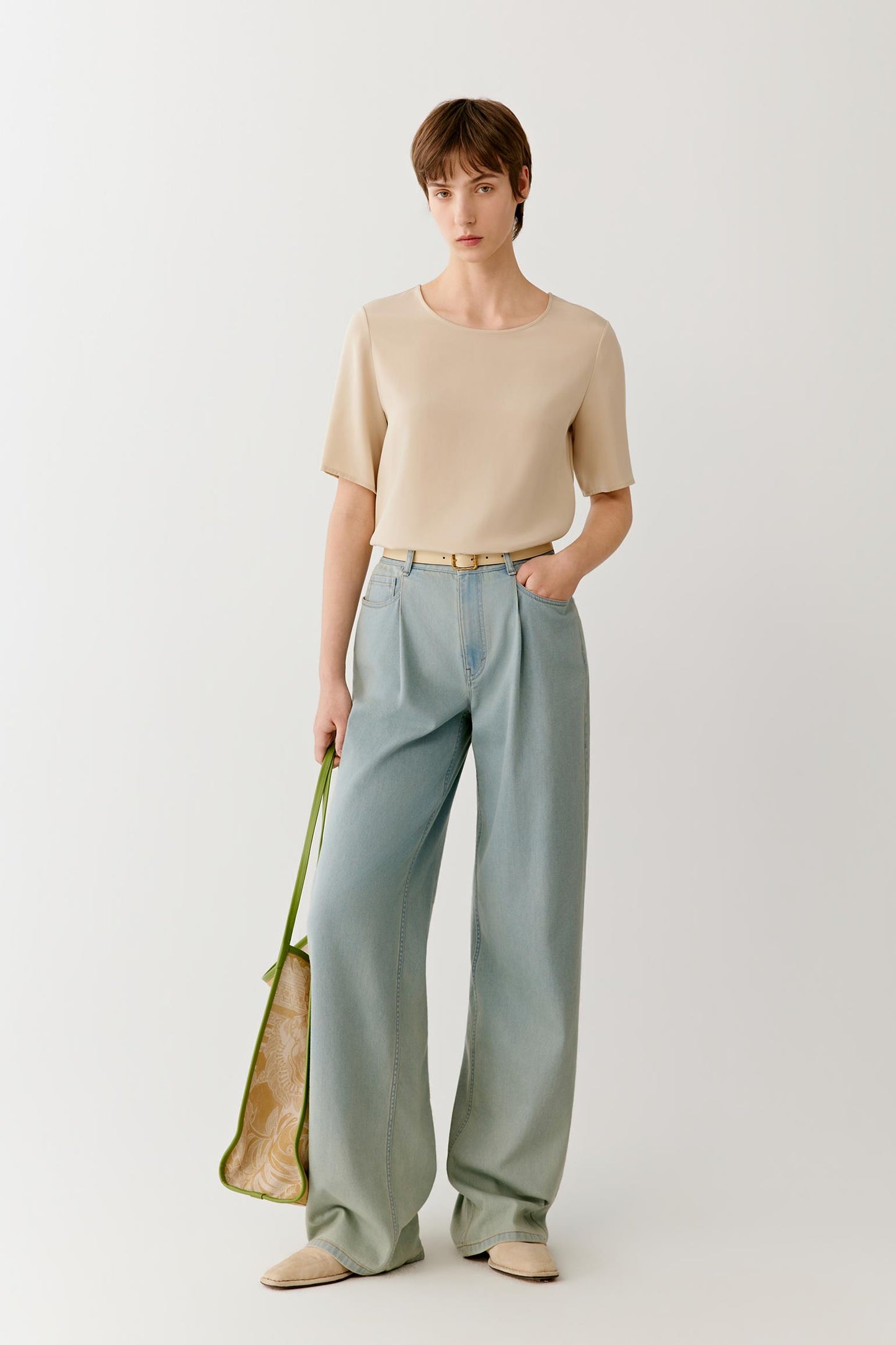 Full-length front view showing the shirt paired with fluid blue-green trousers. The image emphasizes the lightweight construction of the silk crêpe de Chine and the way the fabric drapes softly over the body, creating a balanced and effortless silhouette.