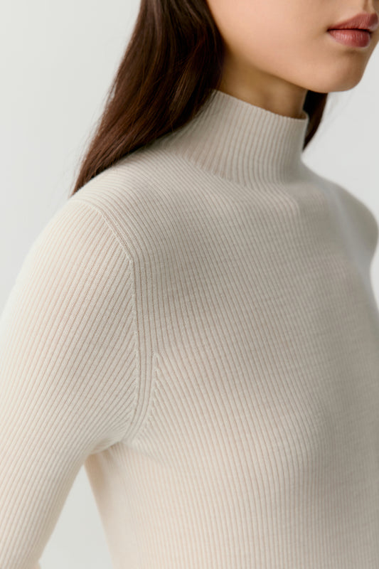 A close-up focuses on the ribbed knit, highlighting the fine, even texture and the softness of the wool against the skin.