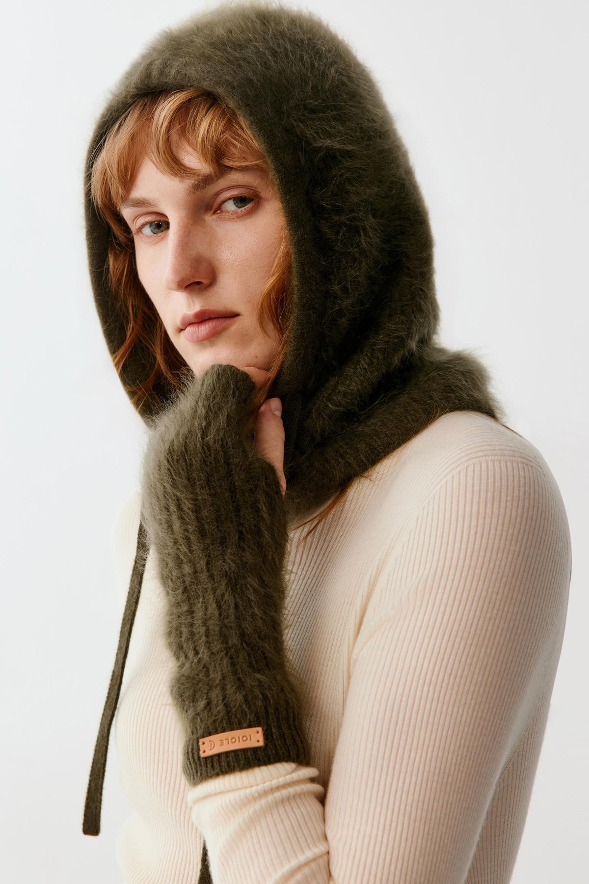 Three-quarter view of a woman wearing the dark green brushed cashmere balaclava, showing the enveloping hood and brushed texture.