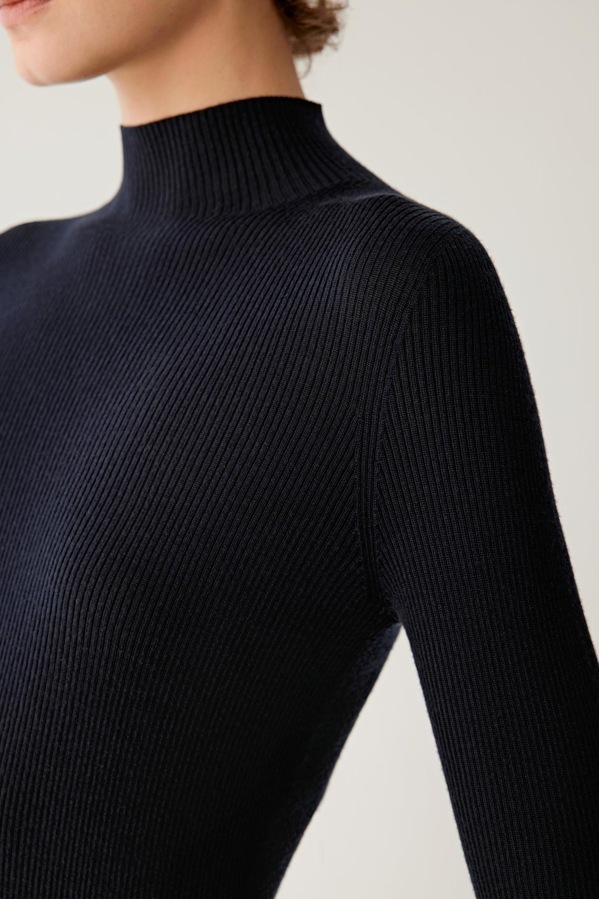 Close-up of navy merino wool pullover showing the mock neckline and fine ribbed knit texture