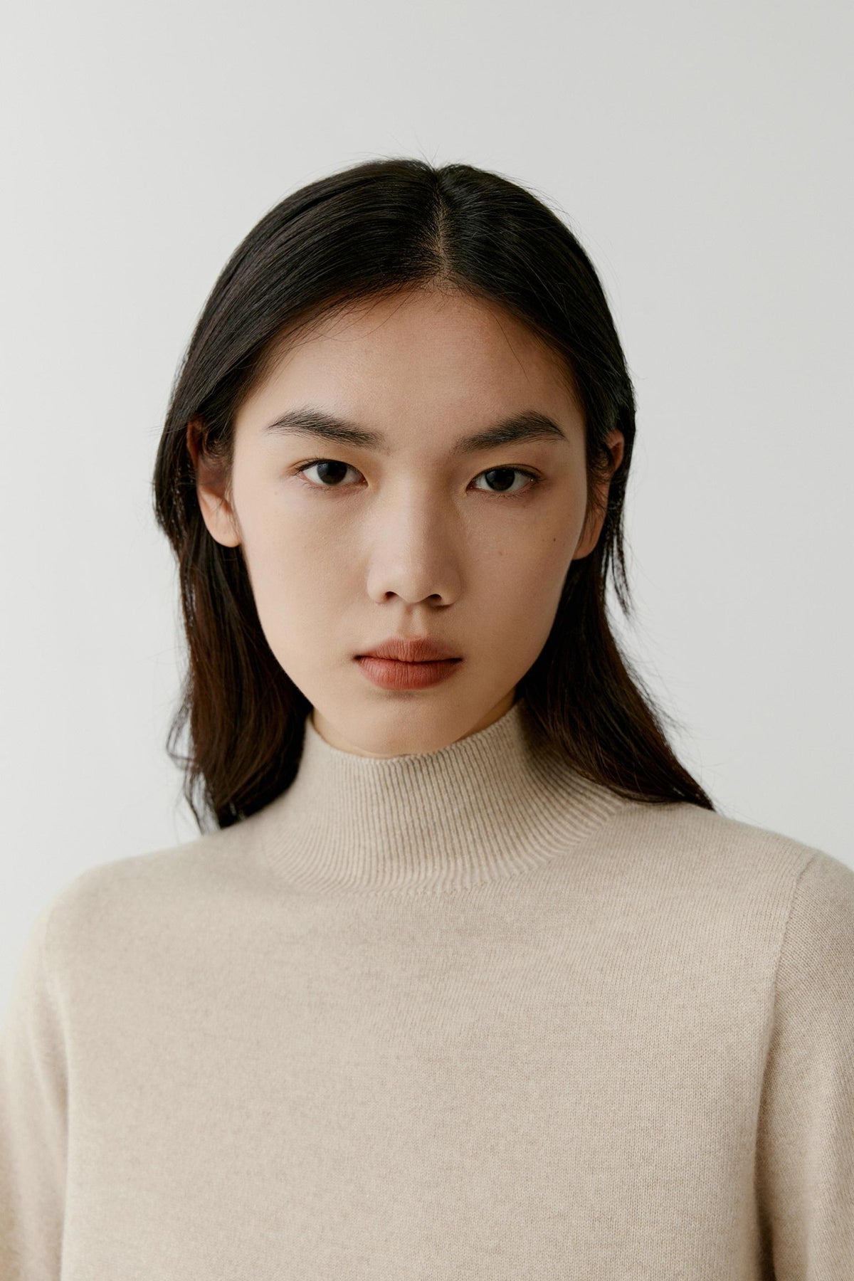 Close-up highlighting the mock neck and fine-knit texture of the beige cashmere pullover.