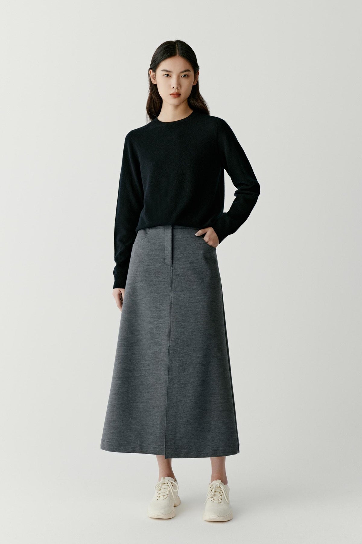 Full-length view of a woman wearing a deep black cashmere pullover, highlighting the relaxed fit and fine-knit construction.
