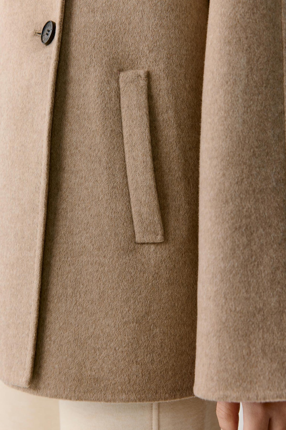 Close-up showing the button fastening, clean edge and dense natural beige double-face cashmere surface.