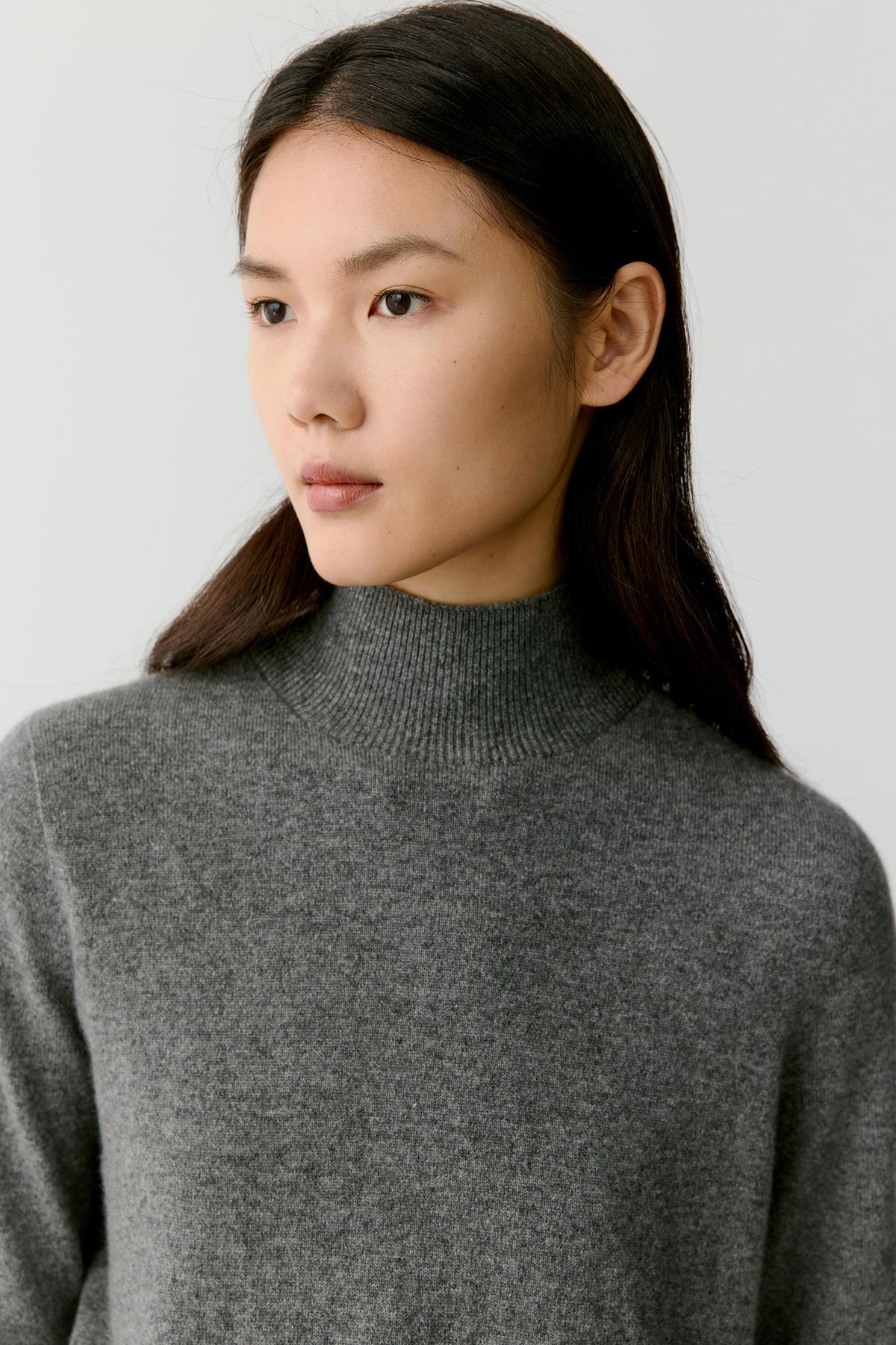 Close-up highlighting the mock neck and fine-knit texture of the smoky grey cashmere pullover.
