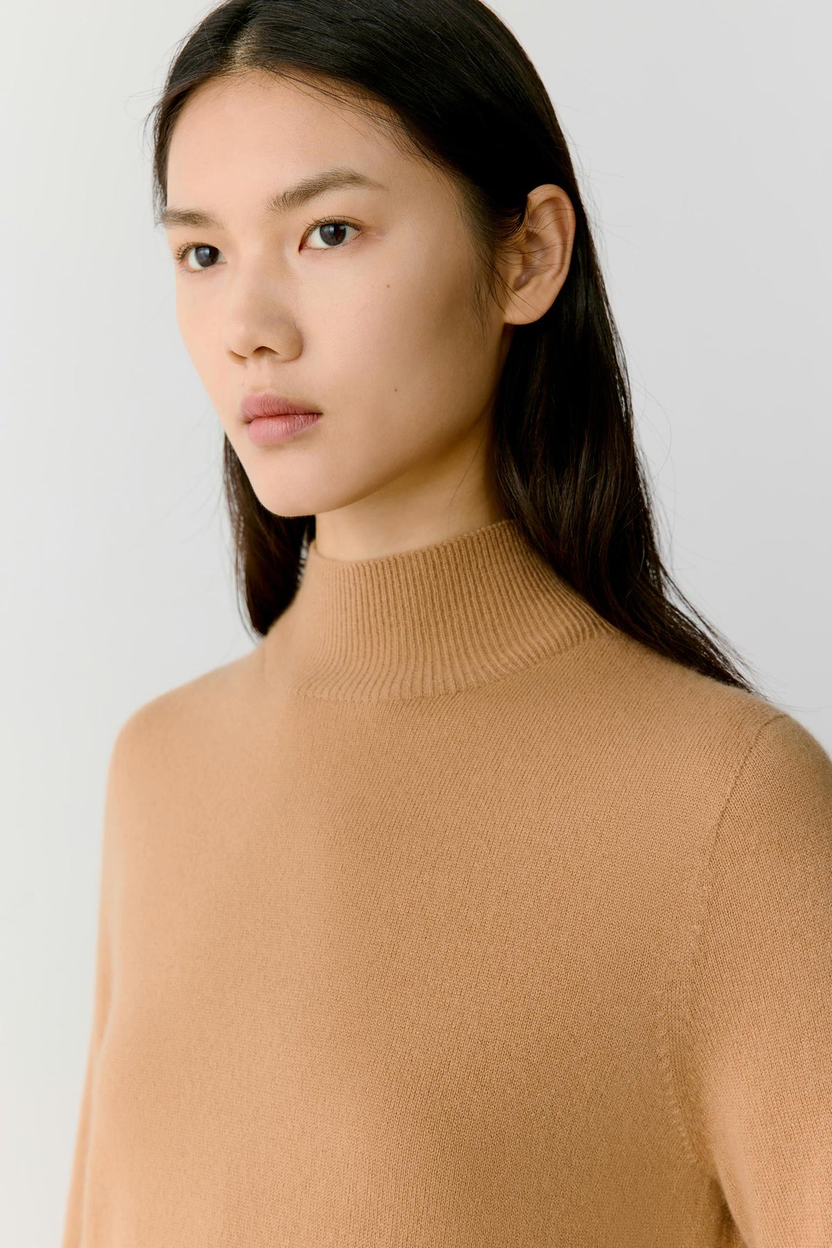 Close-up highlighting the mock neck and fine-knit texture of the camel cashmere pullover.