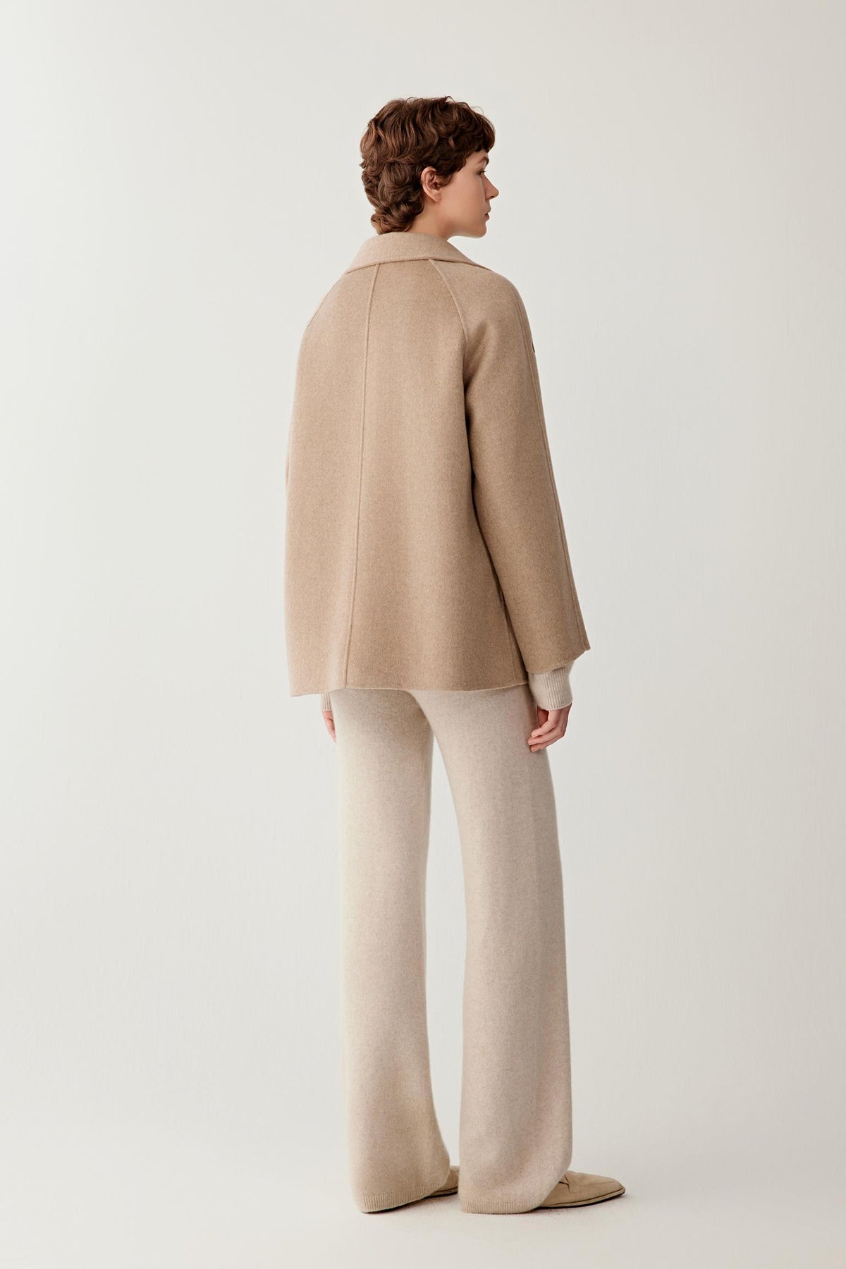 Back view of a woman wearing the natural beige double-face cashmere short coat, showing the relaxed silhouette and clean construction.