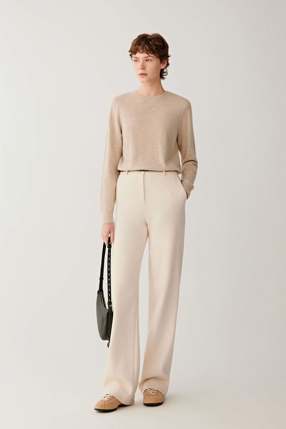 Full-length view of a woman wearing a light beige cashmere pullover, highlighting the relaxed fit and fine-knit construction.