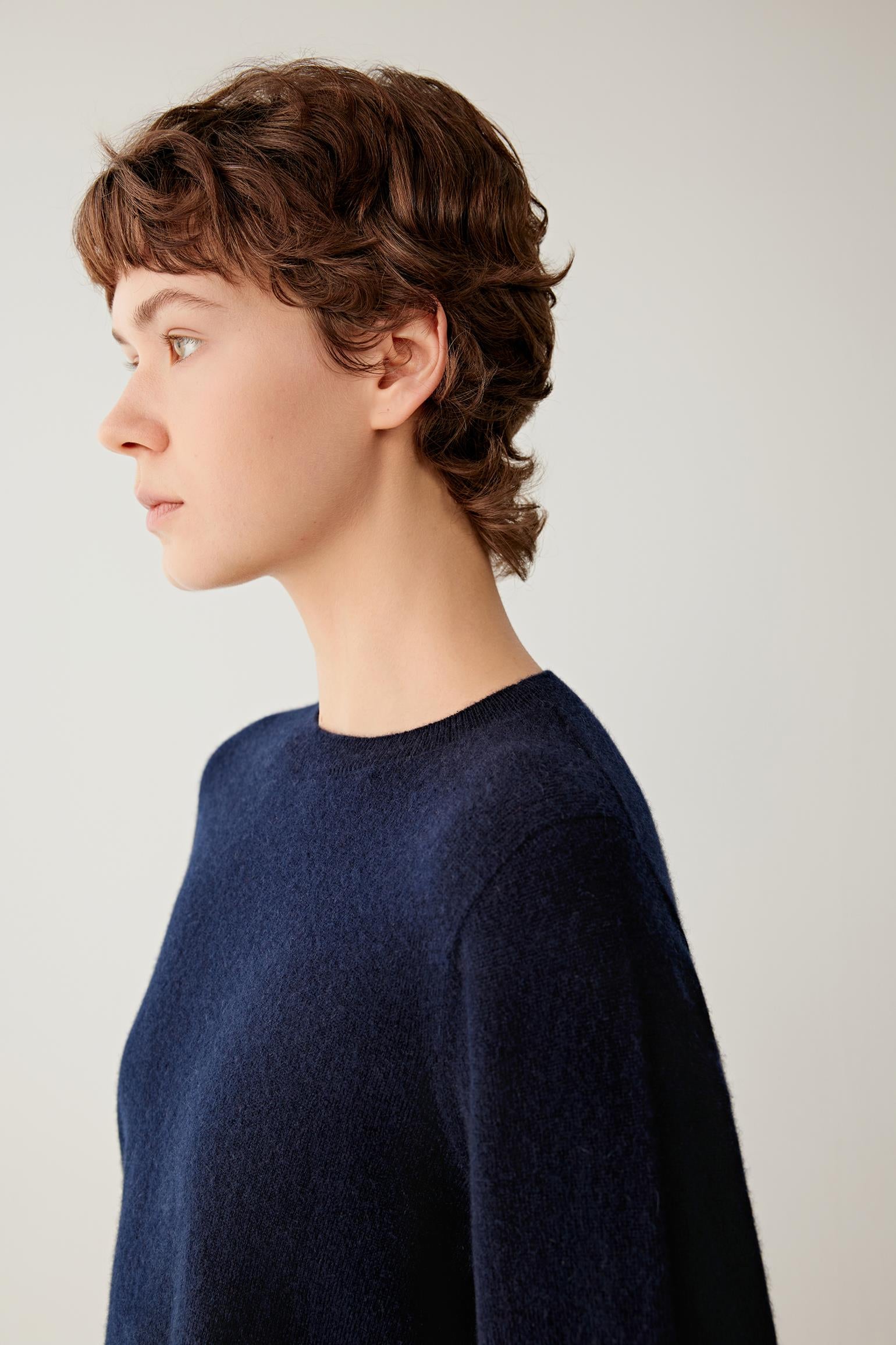 Side close-up of women’s navy cashmere pullover showing the crew neckline and fine-gauge knit texture