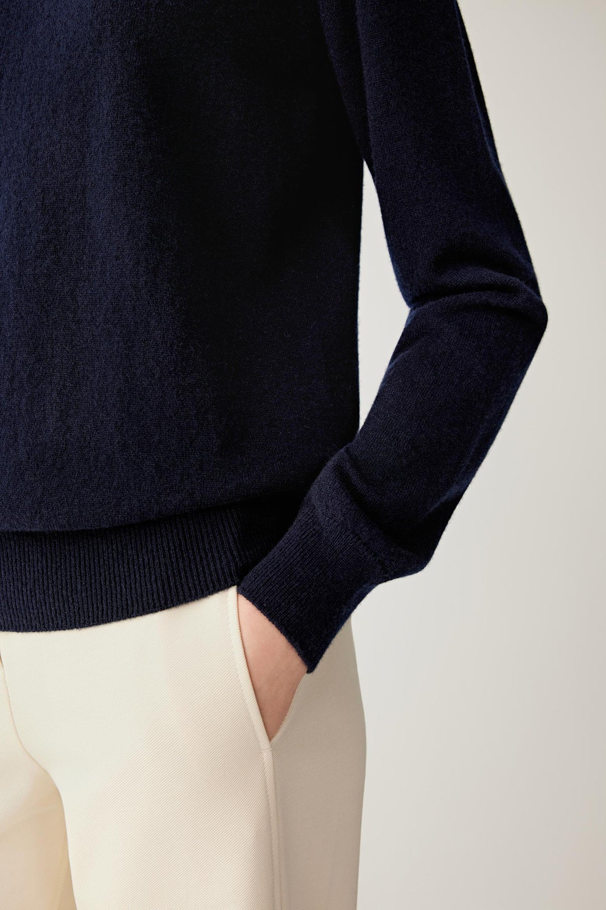 Close-up of navy cashmere pullover showing the long sleeve, ribbed cuff and hem detail