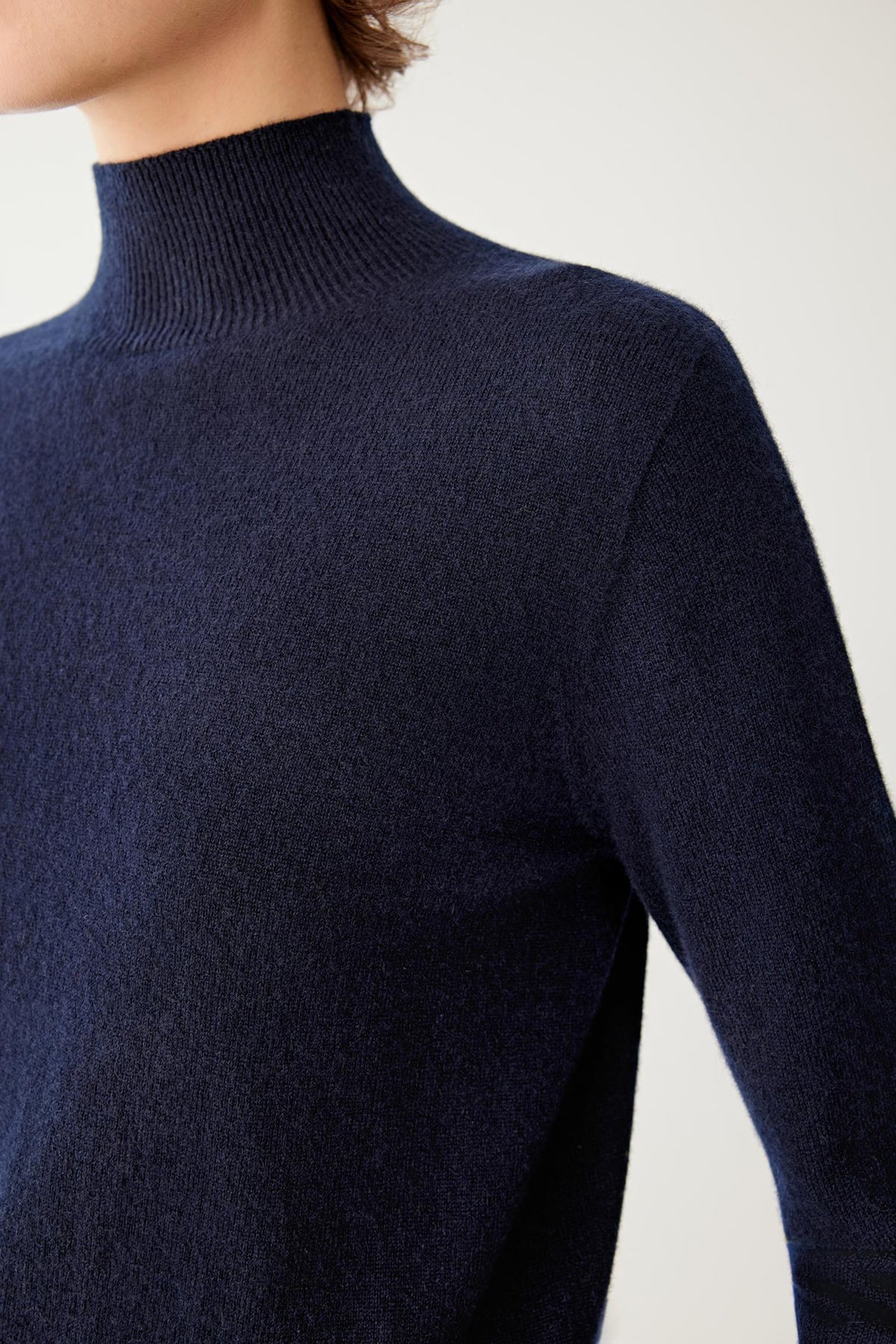 Close-up highlighting the mock neck and smooth fine-knit texture of the navy cashmere pullover.
