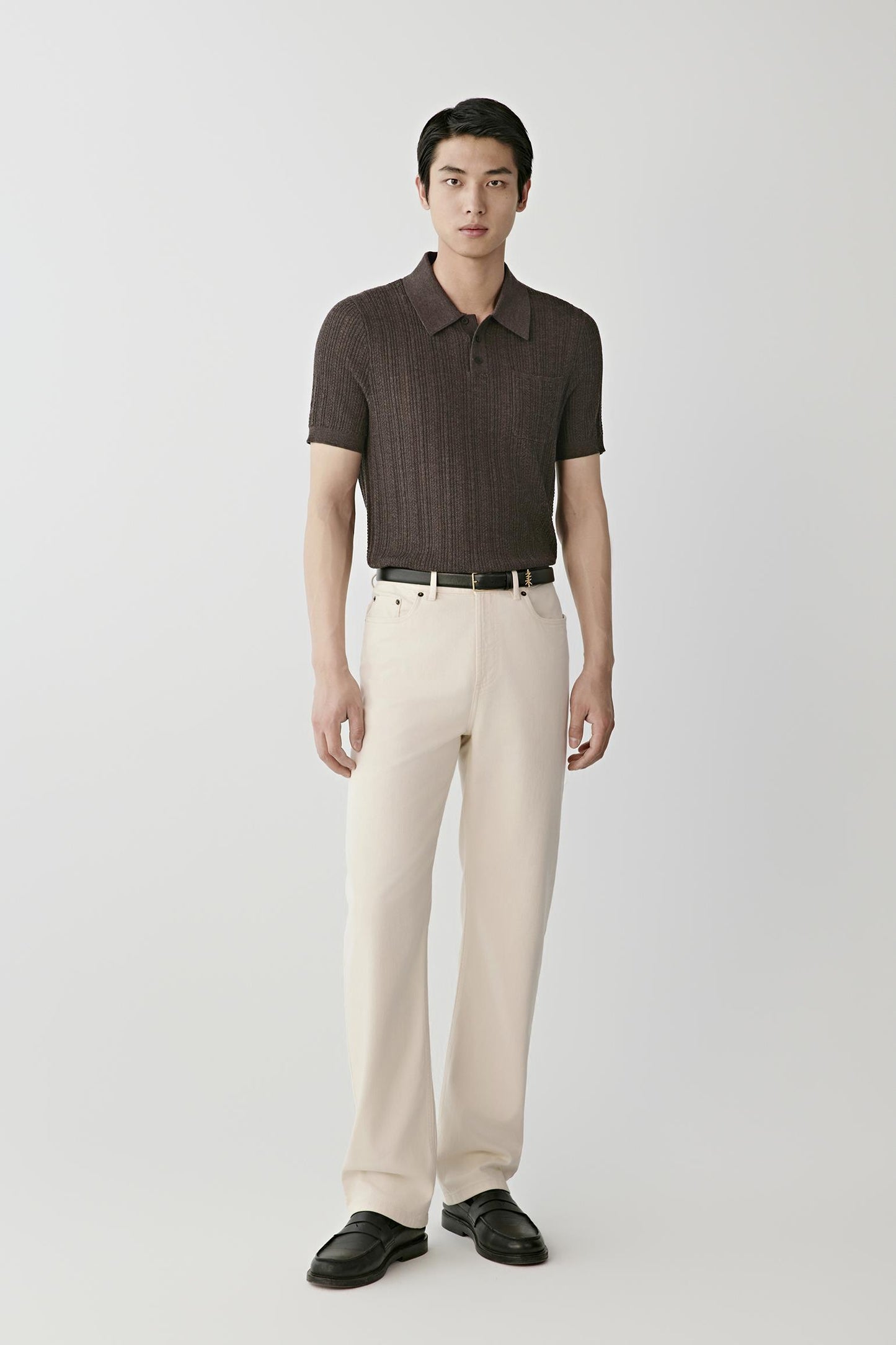 Man wearing a brown knitted polo shirt with cream trousers and black loafers.