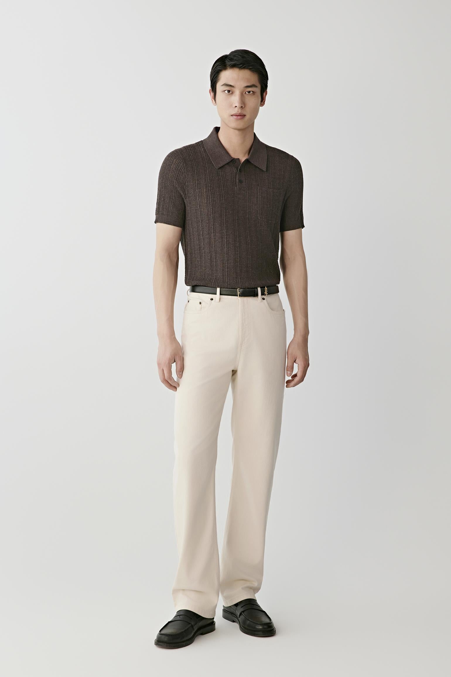 Man wearing a brown knitted polo shirt with cream trousers and black loafers.