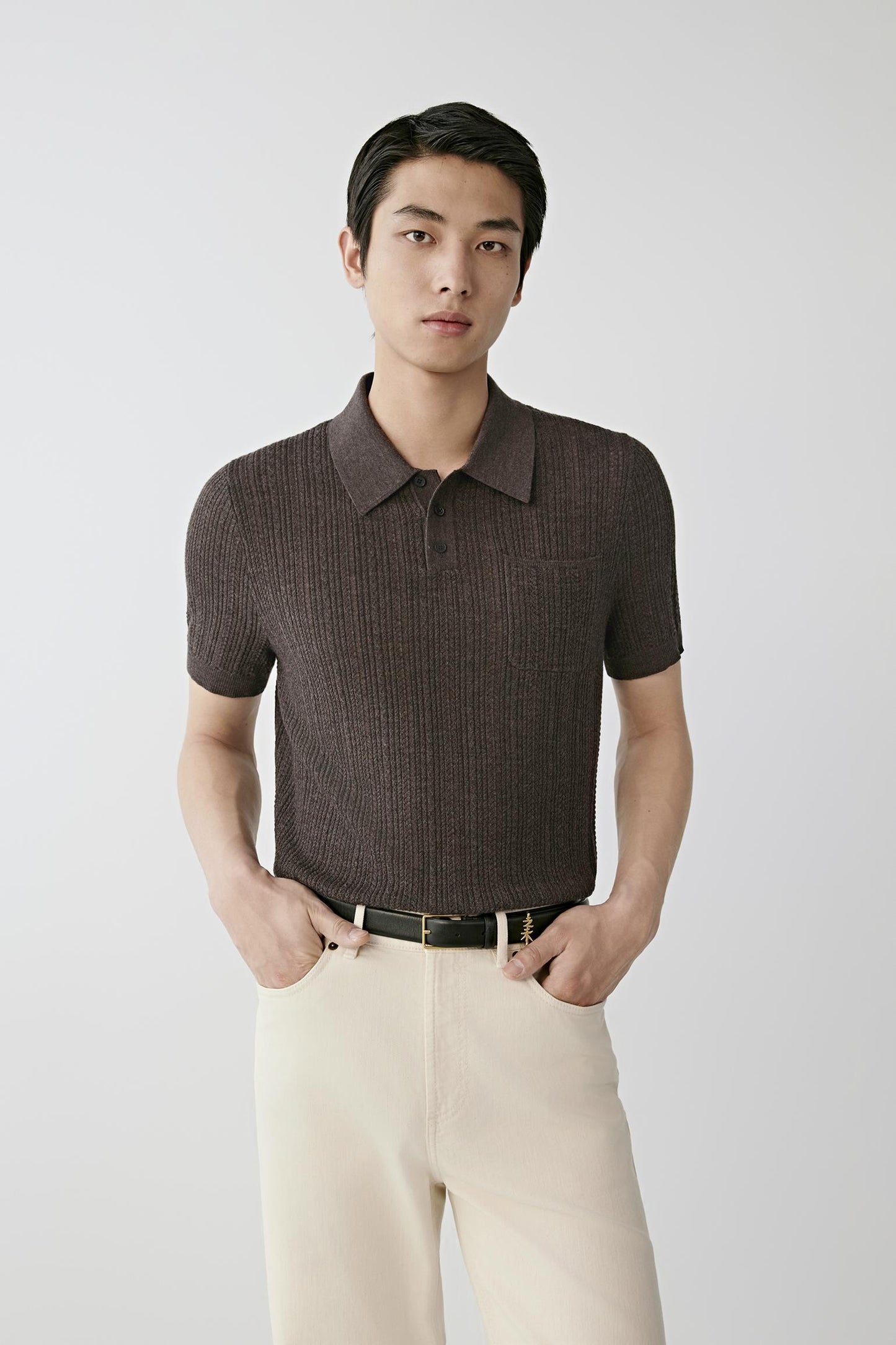 Man wearing a brown knitted polo shirt with cream trousers.