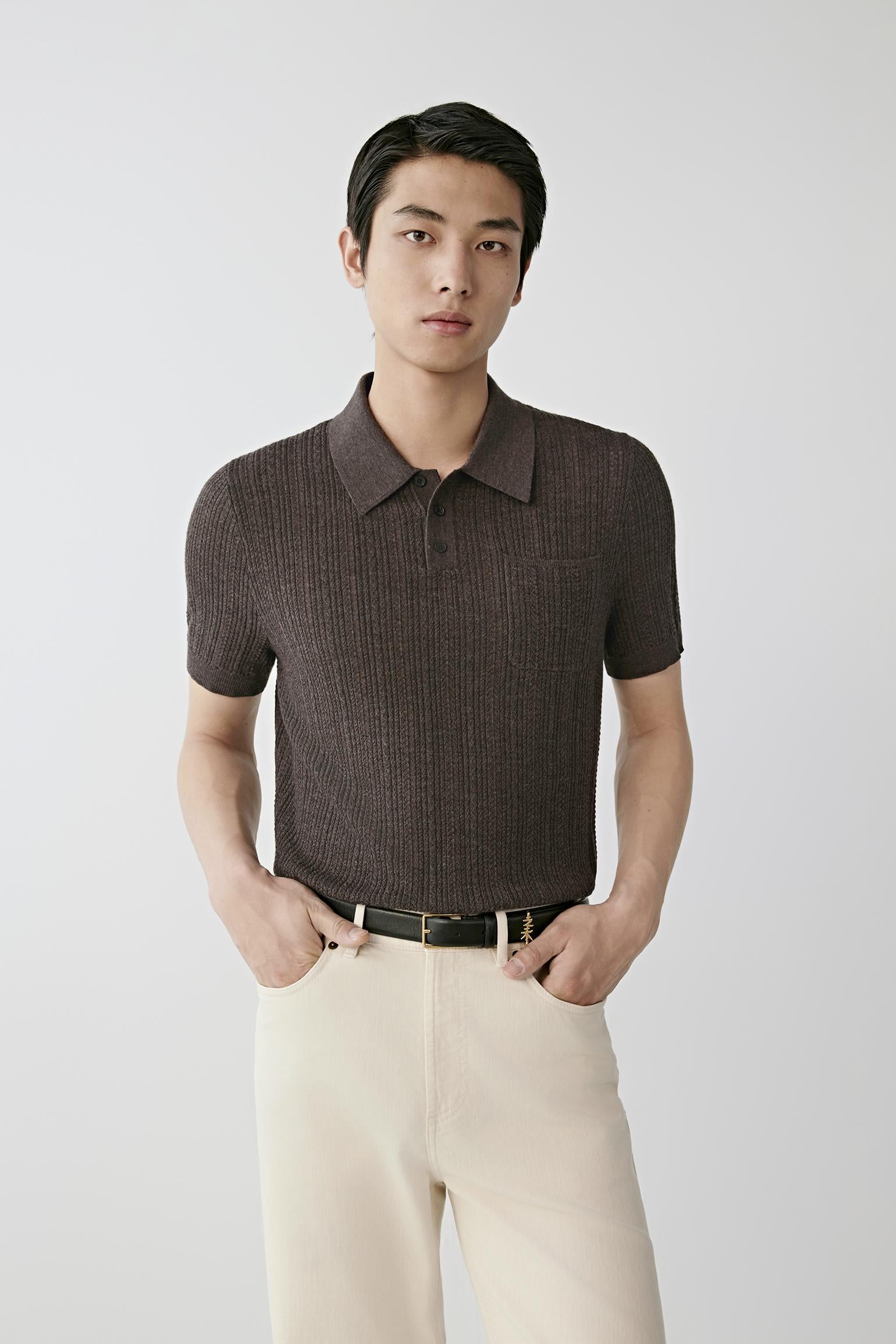 Man wearing a brown knitted polo shirt with cream trousers.