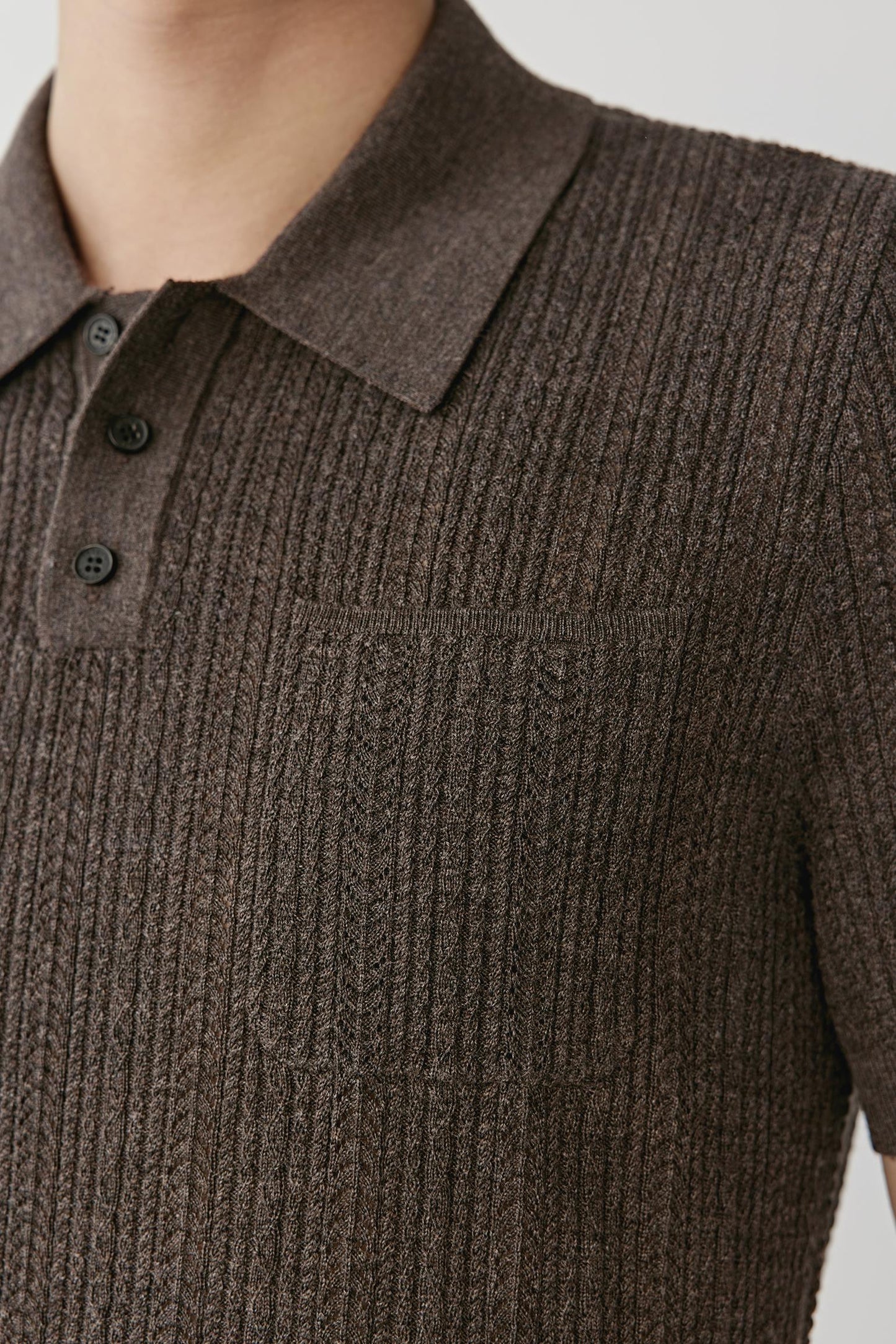 Close up of a man wearing a brown knitted polo