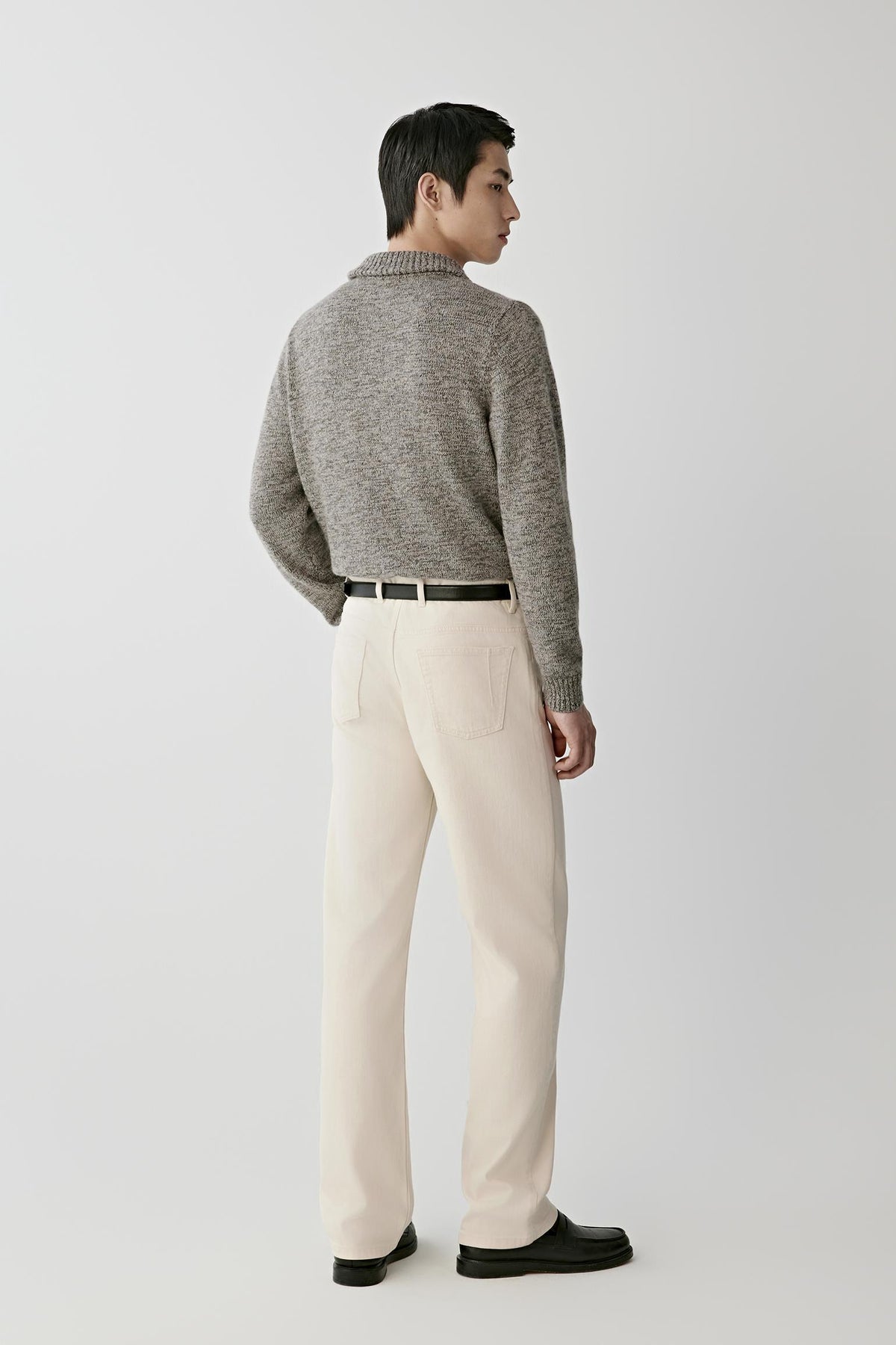 Back view of a man wearing the grey melange twisted cashmere cardigan, showing the straight silhouette and textured melange knit.