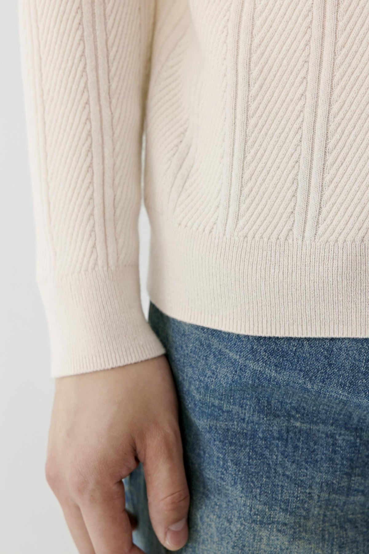 Close-up highlighting the ribbed hem, long sleeve and textured white cashmere knit.