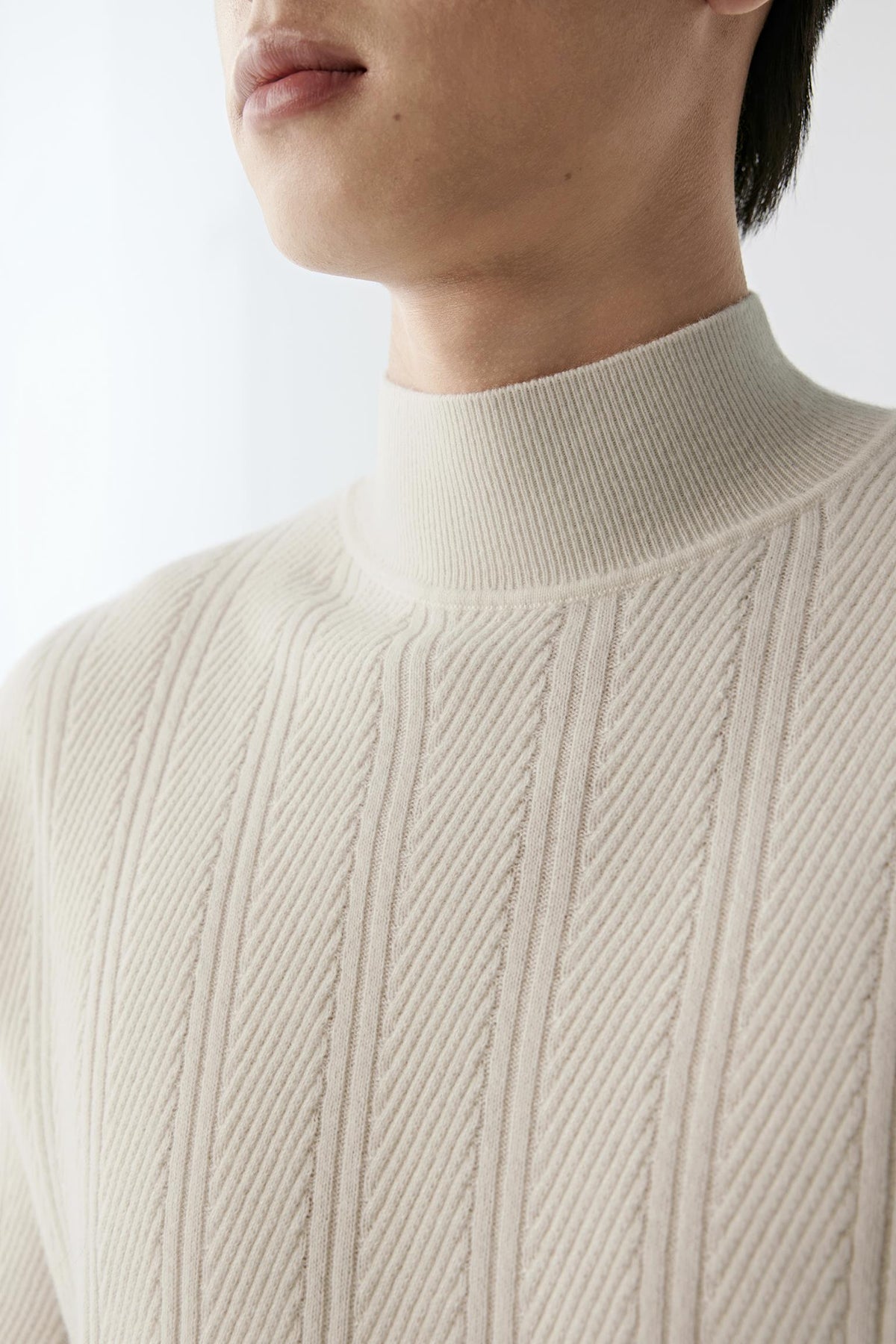 Close-up highlighting the cable knit and vertical rib texture of the white cashmere pullover.