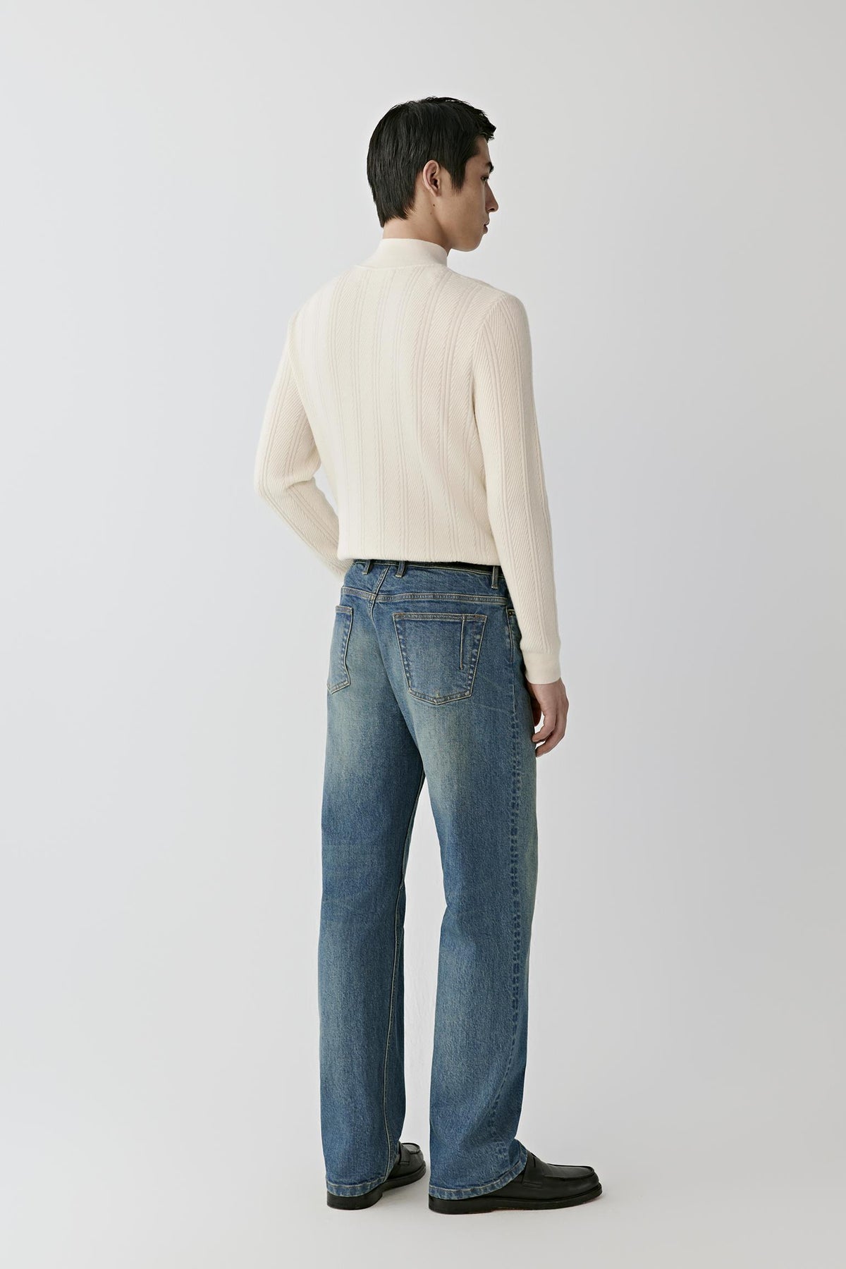 Back view of a man wearing the white cashmere pullover, showing the mock neck and vertical rib detailing.