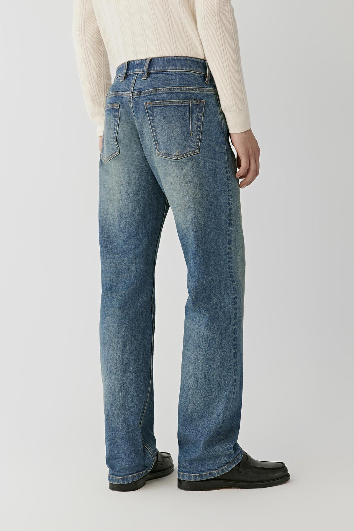 Back view of the blue denim jeans, showing the loose-leg silhouette and back pockets.