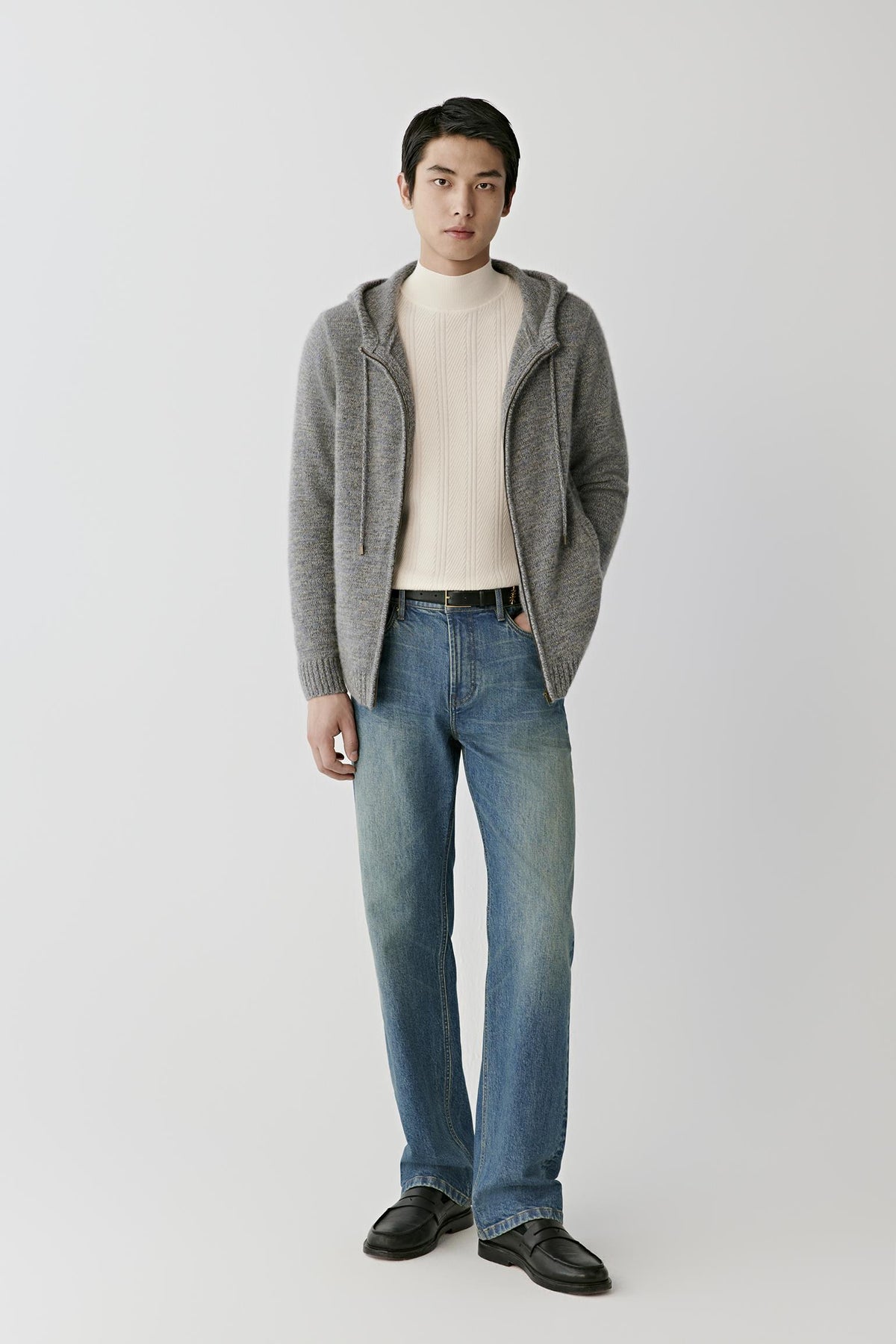 Front full-length view of a man wearing the grey melange twisted cashmere cardigan, showing the hood, long sleeves and straight silhouette.