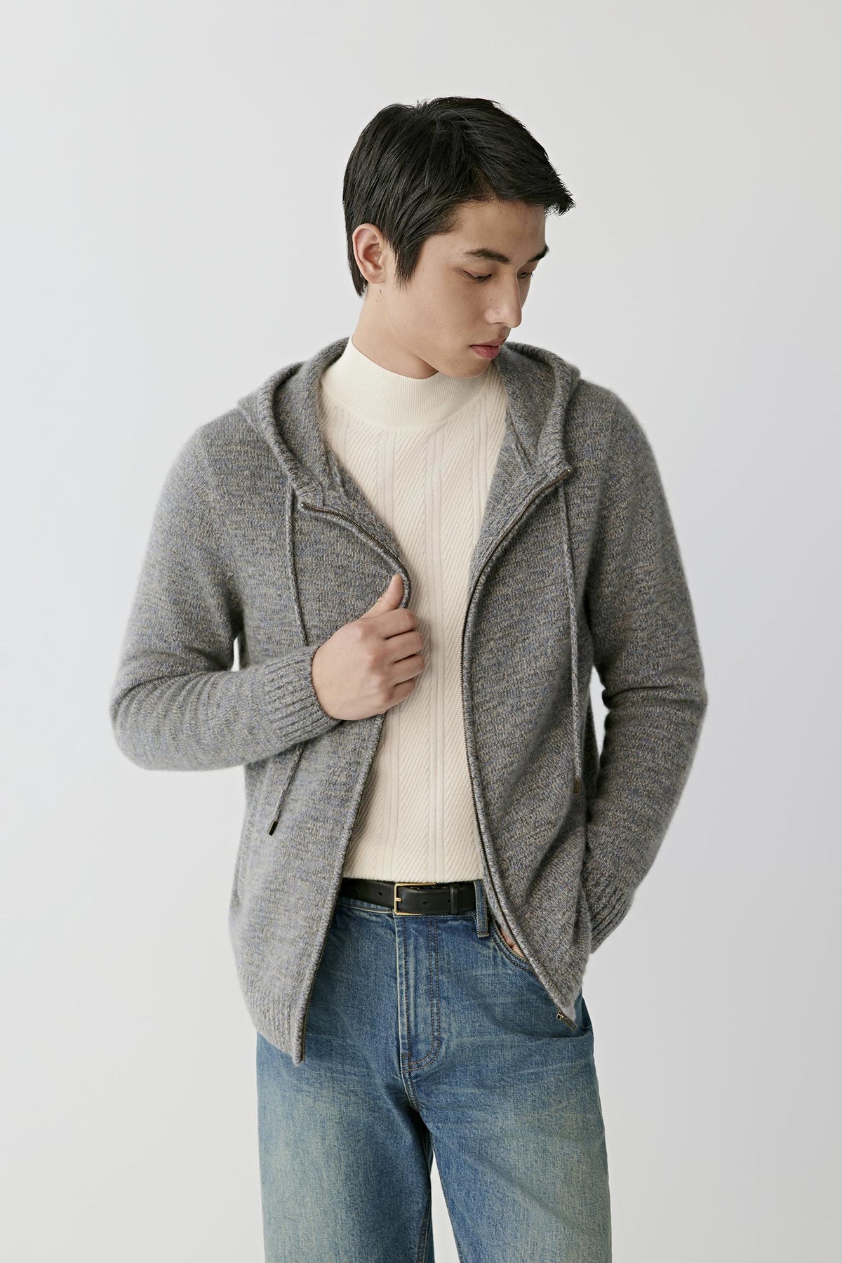 Front view of a man wearing a grey melange twisted cashmere cardigan, showing the hood, front zip fastening and relaxed silhouette.