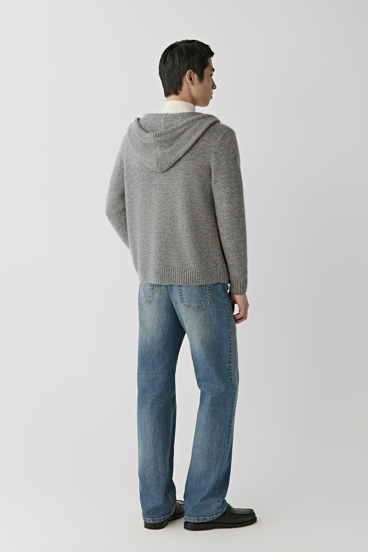 Back view of a man wearing the grey melange twisted cashmere cardigan, showing the hood and straight silhouette.