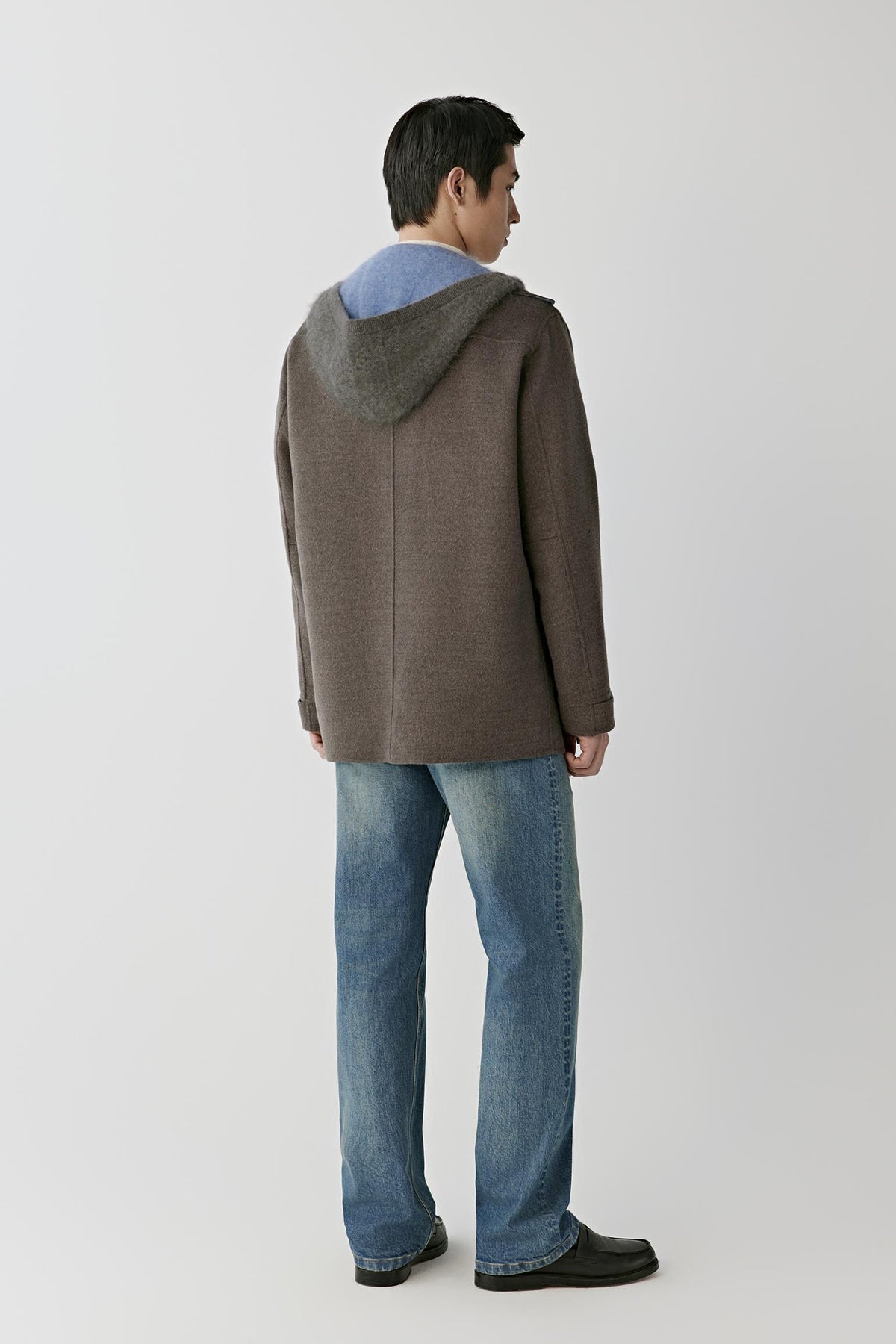 Back view of a man wearing the dark brown melange merino wool coat, showing the detachable hood and straight silhouette.