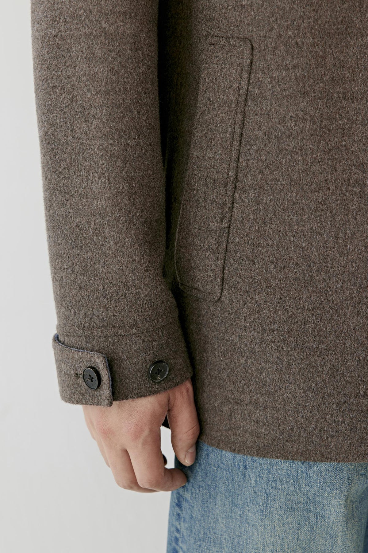 Close-up highlighting the adjustable buttoned cuff and dark brown melange merino wool texture.