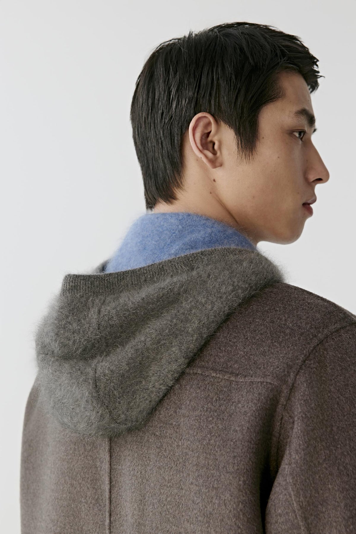 Close-up from the back highlighting the detachable hood and dark brown melange wool texture.