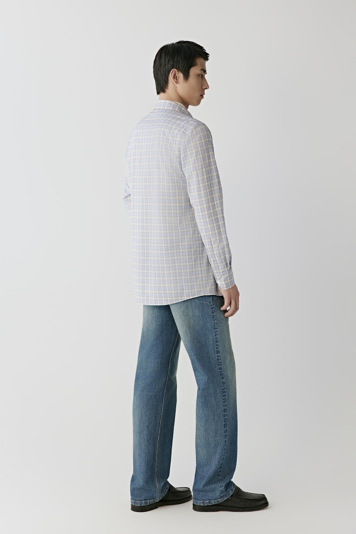 Back view of a man wearing the checked worsted wool shirt, showing the straight silhouette and checked pattern.