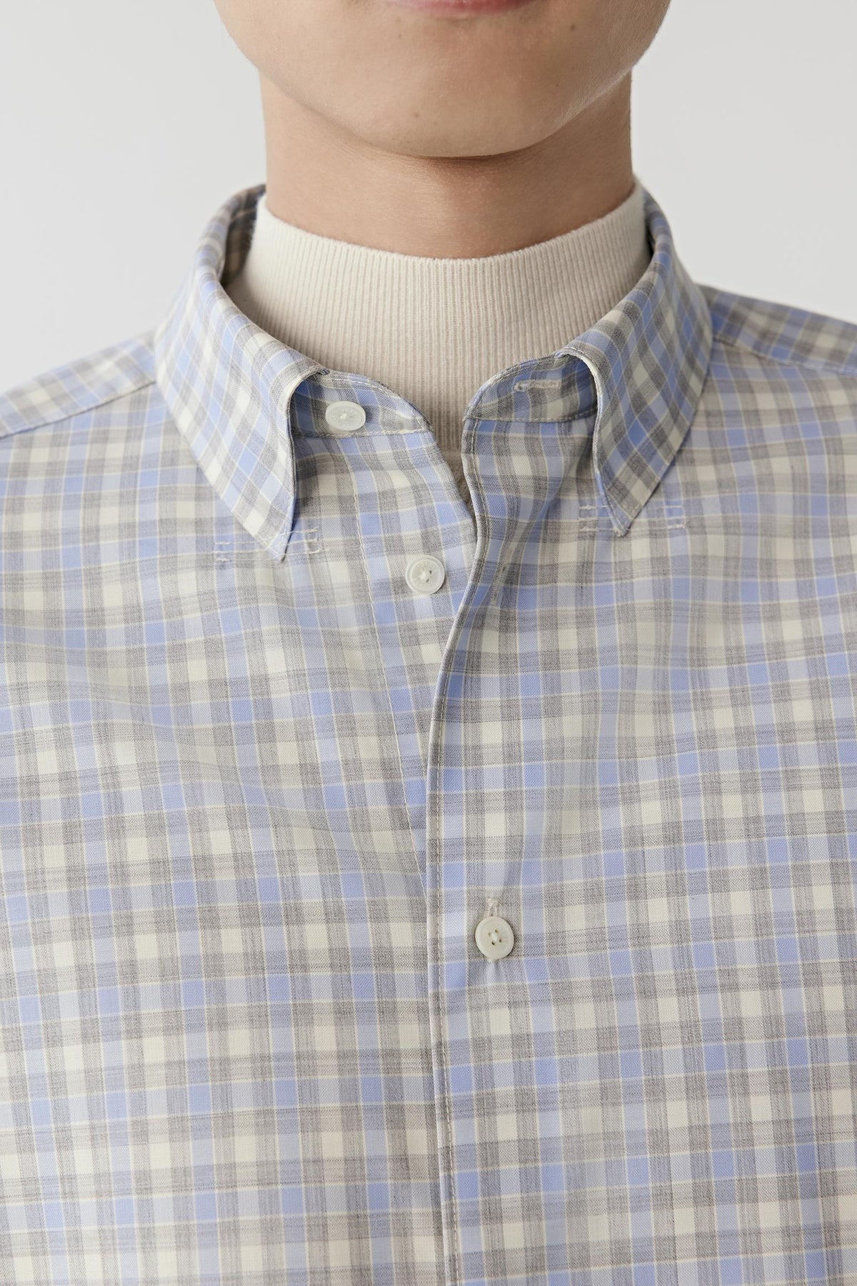 Close-up highlighting the classic collar, button-front fastening and blue, grey and white checked pattern.
