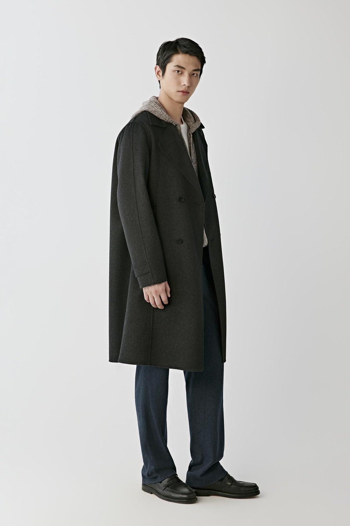Three-quarter view of a man wearing the dark grey double-face cashmere coat, highlighting the notched lapels and double-breasted construction.
