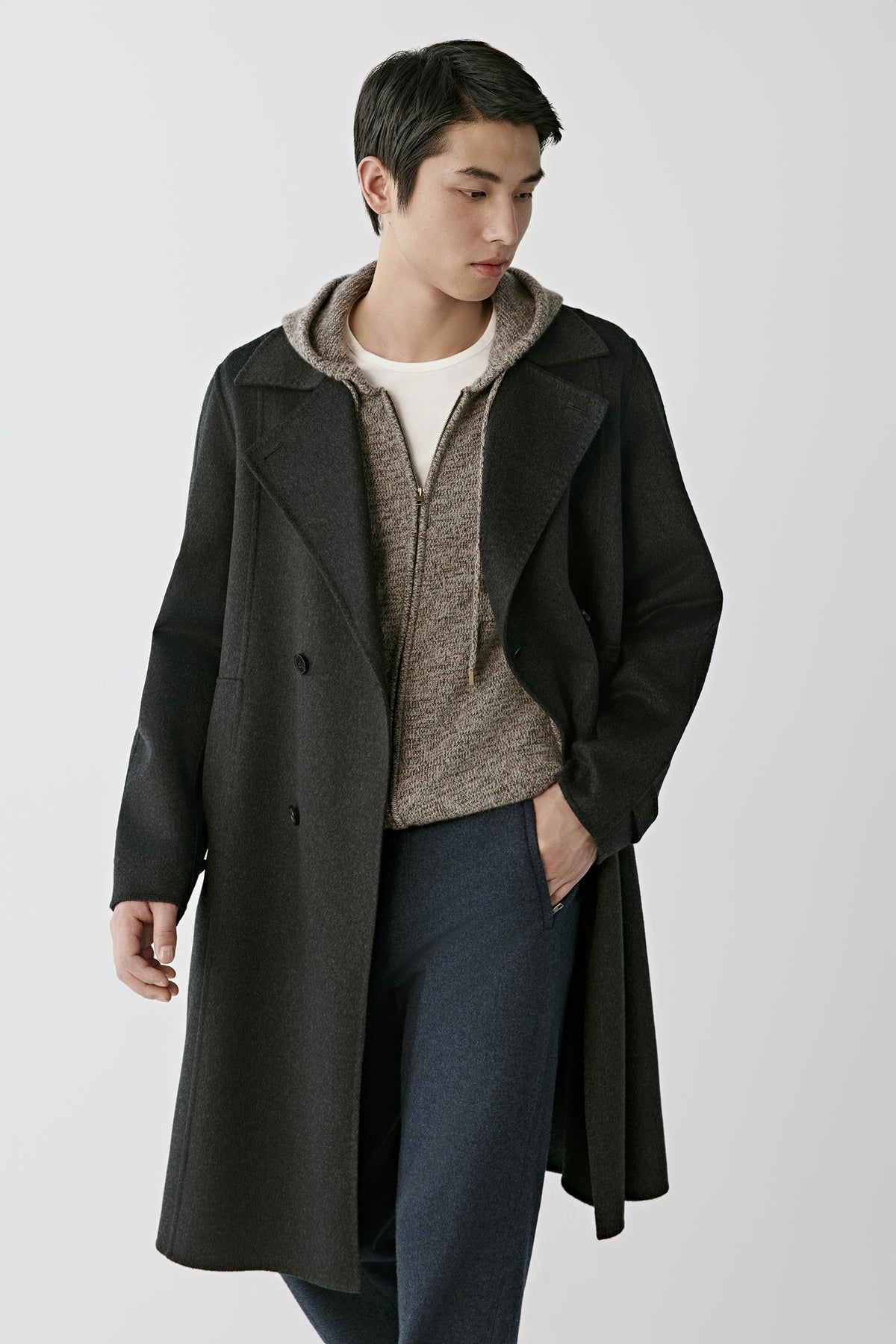 Front view of a man wearing a dark grey double-face cashmere coat, showing the notched lapels, double-breasted fastening and long silhouette.