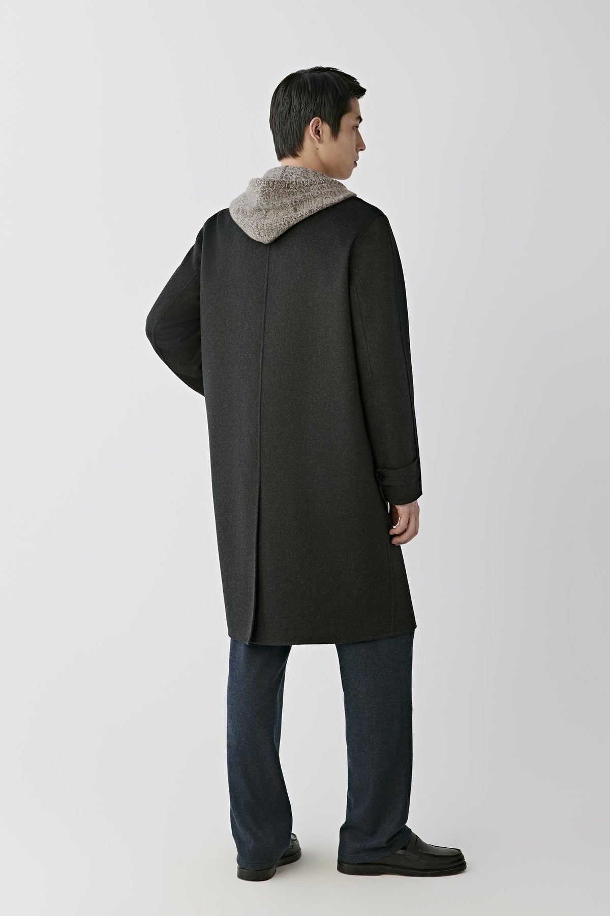 Back view of a man wearing the dark grey double-face cashmere coat, showing the long straight silhouette and back vent.