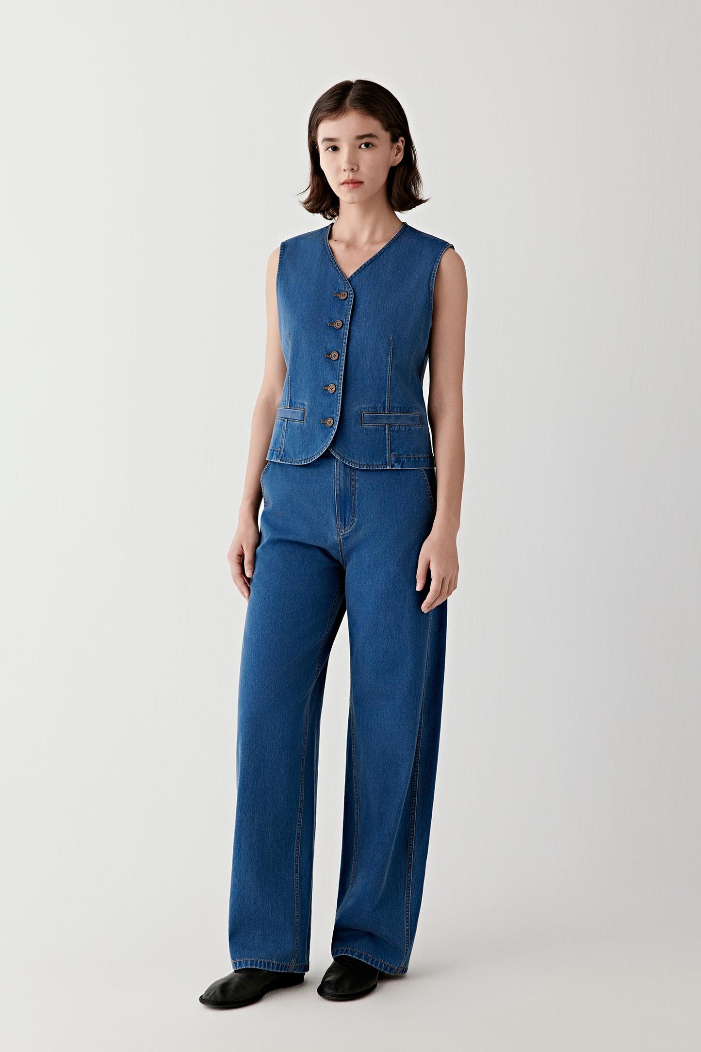Full-length view of the denim vest styled with matching straight-leg jeans, highlighting the coordinated set, vertical silhouette and clean construction.
