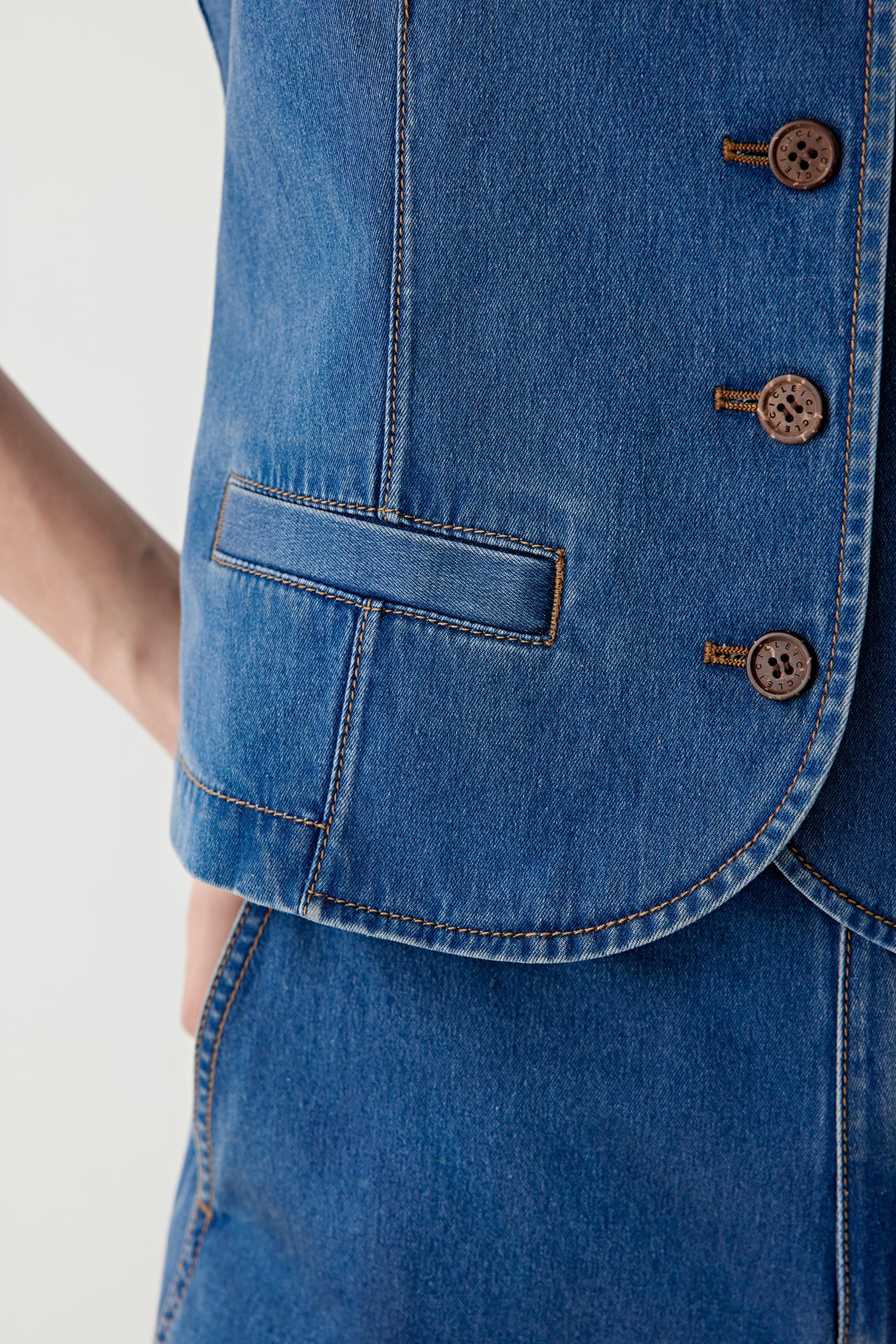 Close-up of the front button placket and hem, highlighting the contrast stitching, metal buttons and precise finishing of the denim fabric.